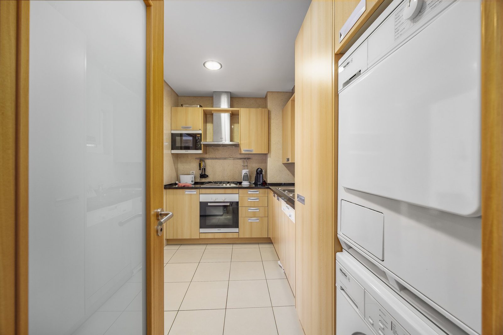 Kitchen with oven, hob, and stacked washer-dryer