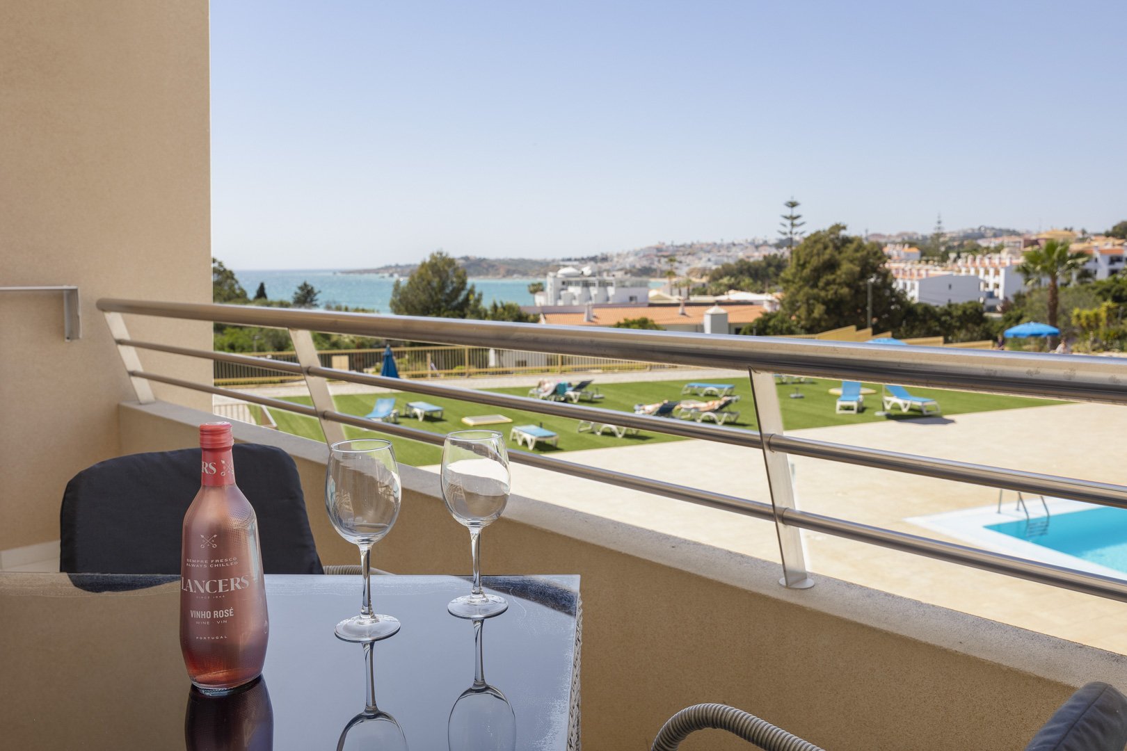 Balcony table with wine glasses and coastal view