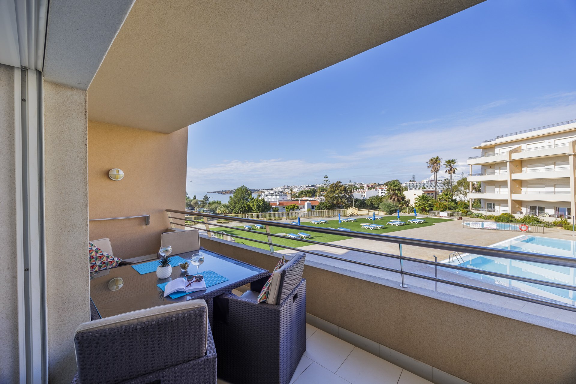 Balcony with wide view over the pool, sea, and town