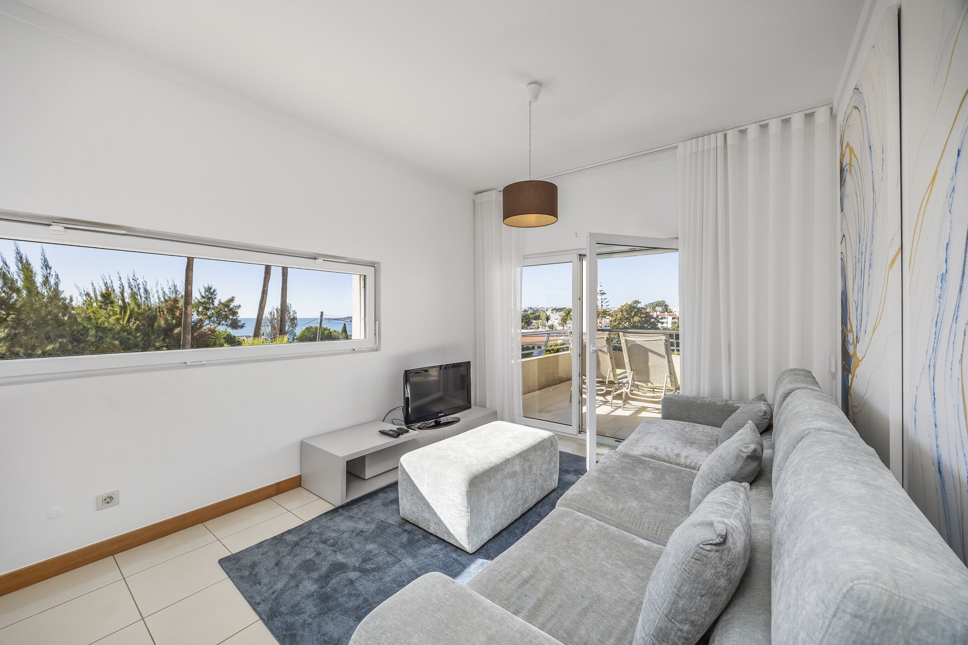 Living room with sofa, TV, and sea view window