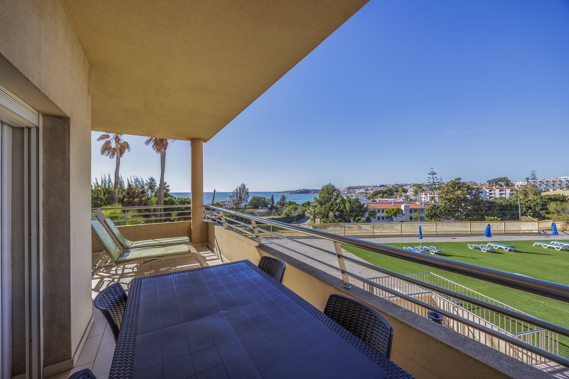 Terrace with sun lounger, palm trees, and coastal view