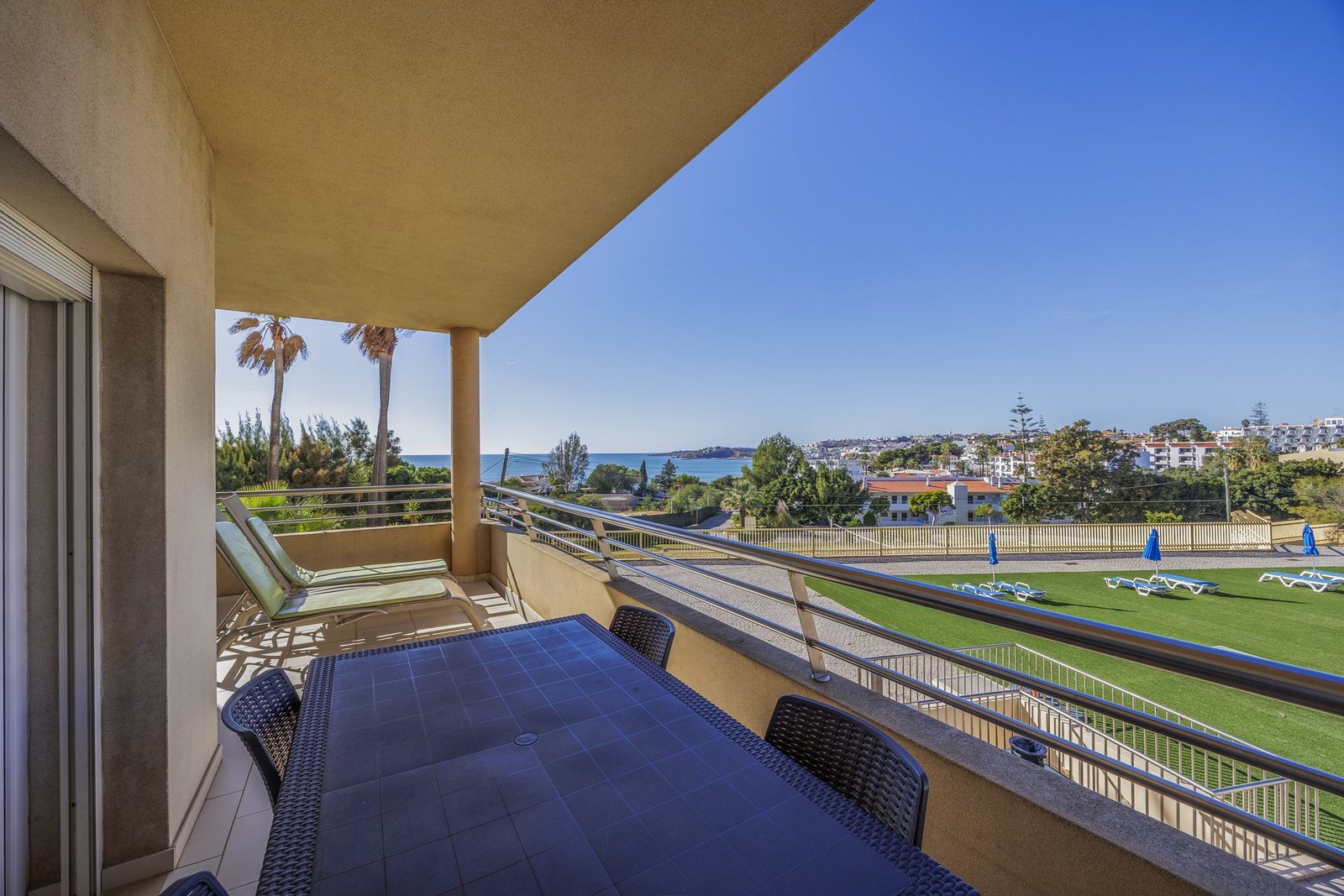 Terrace with sun lounger, palm trees, and coastal view