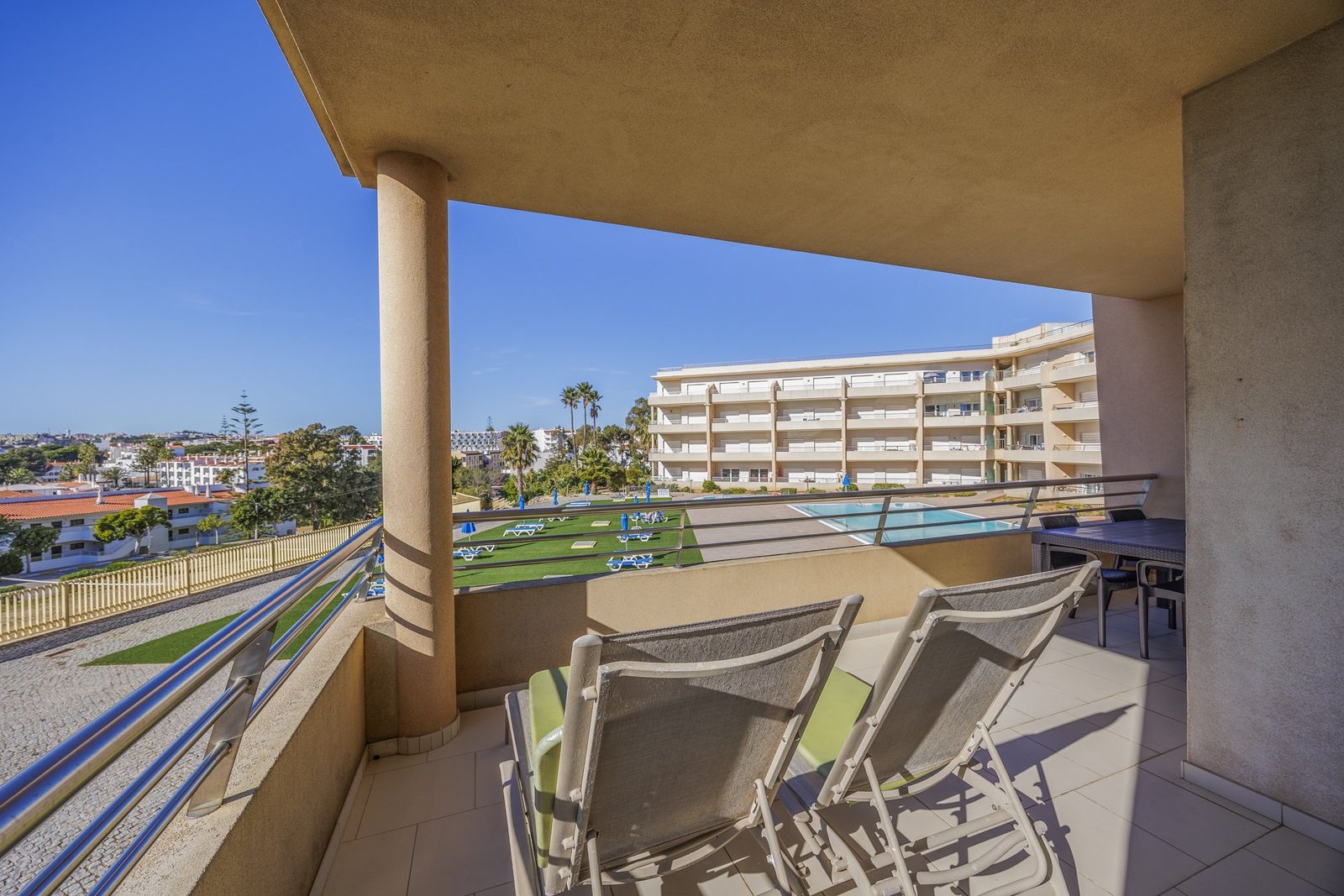 Terrace with dining table and sun loungers overlooking the pool