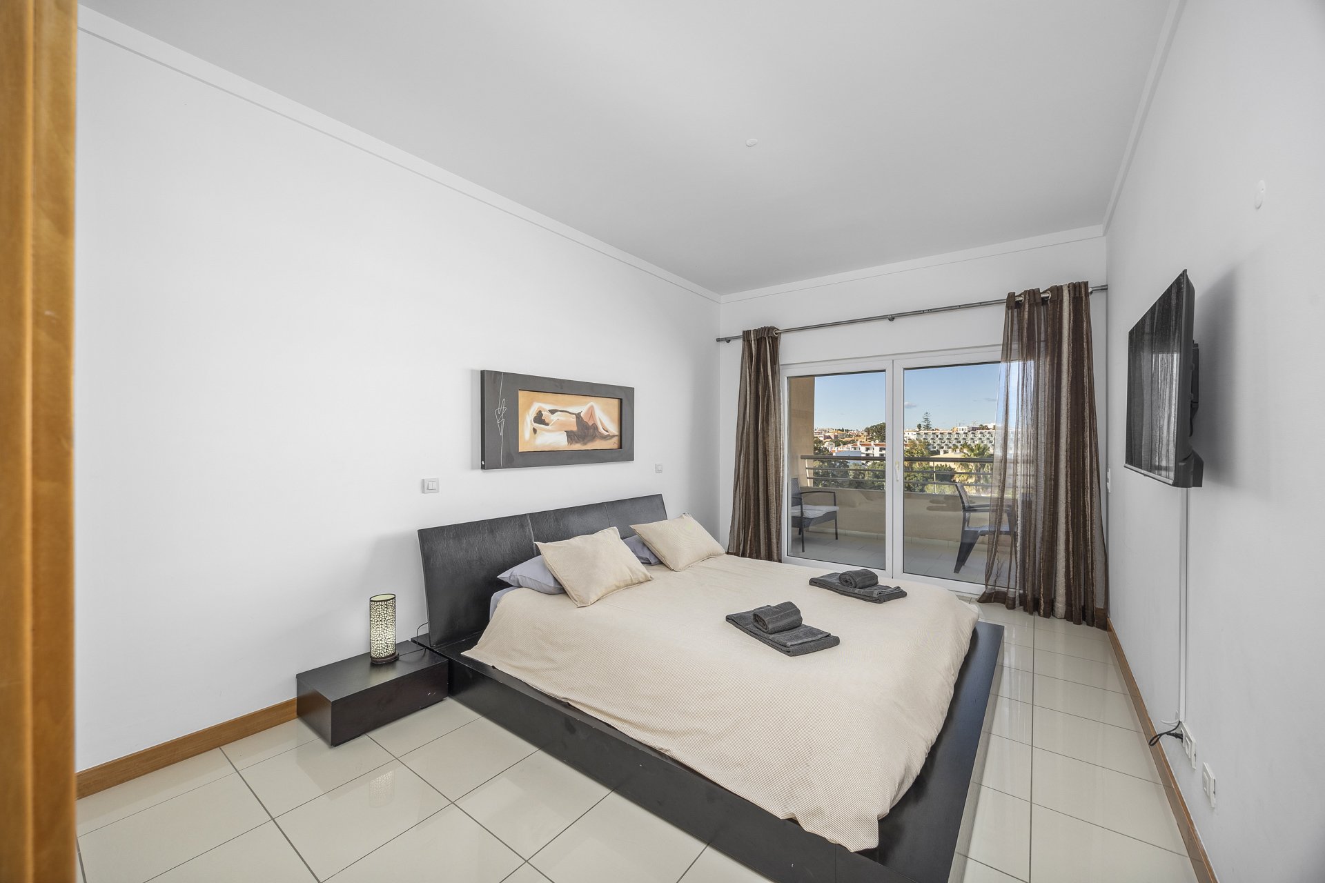 Bedroom with double bed, TV, and balcony access