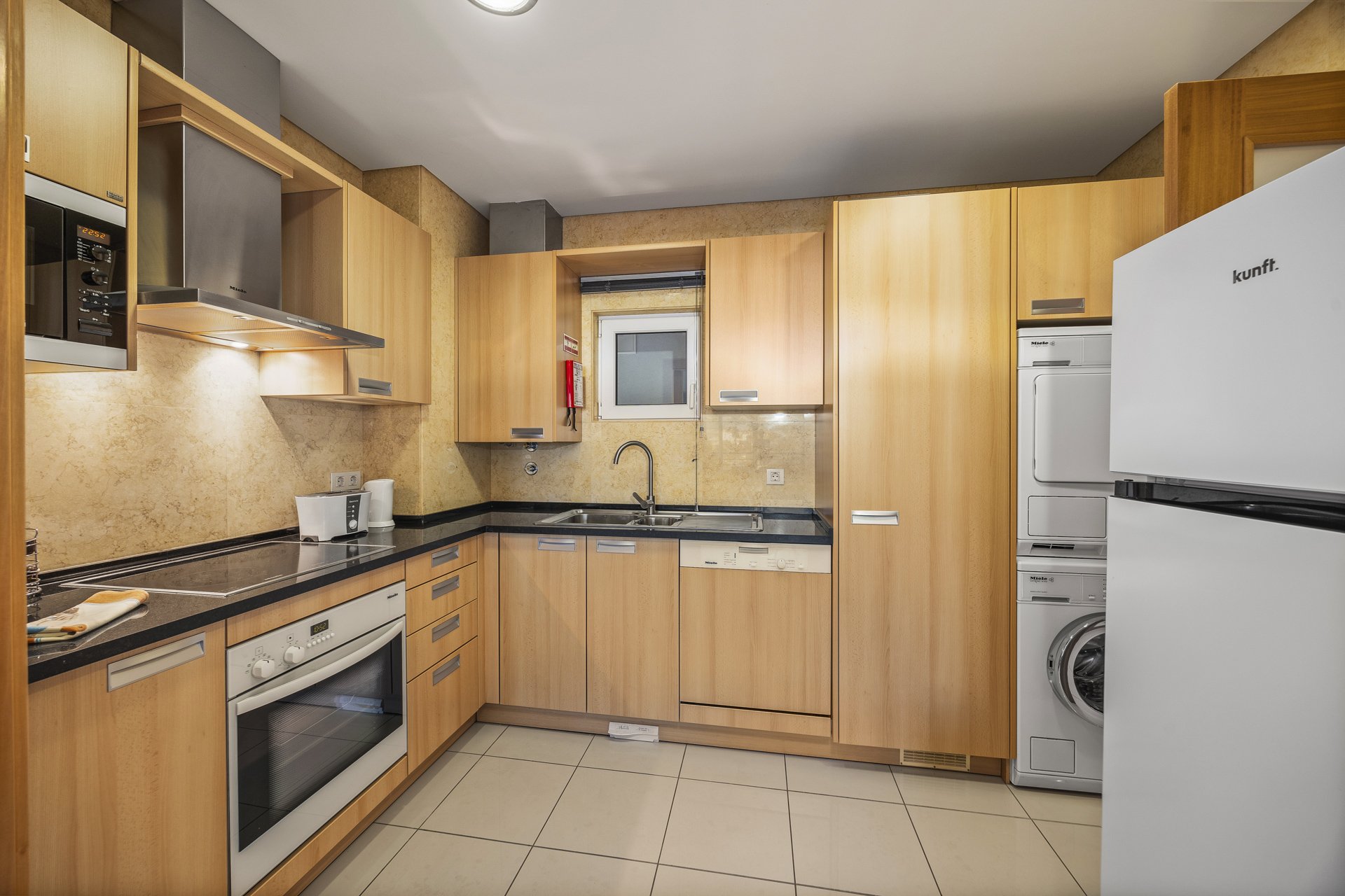 Kitchen with fridge, oven, hob, and washer-dryer