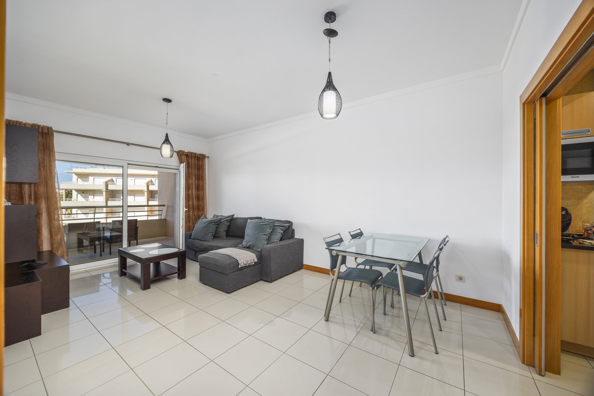 Living and dining area with sofa, dining table, and balcony access