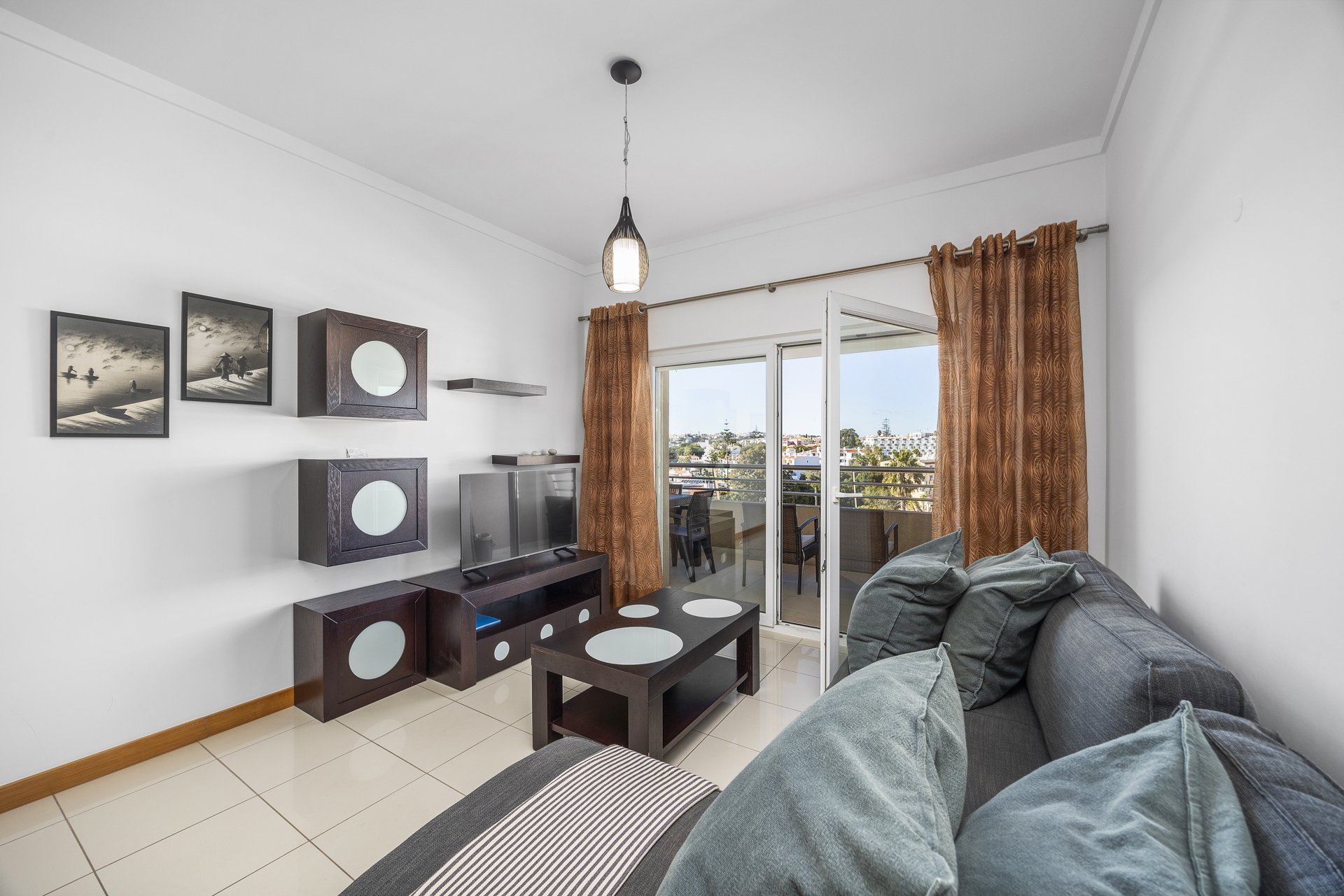 Living room with sofa, TV, and balcony access