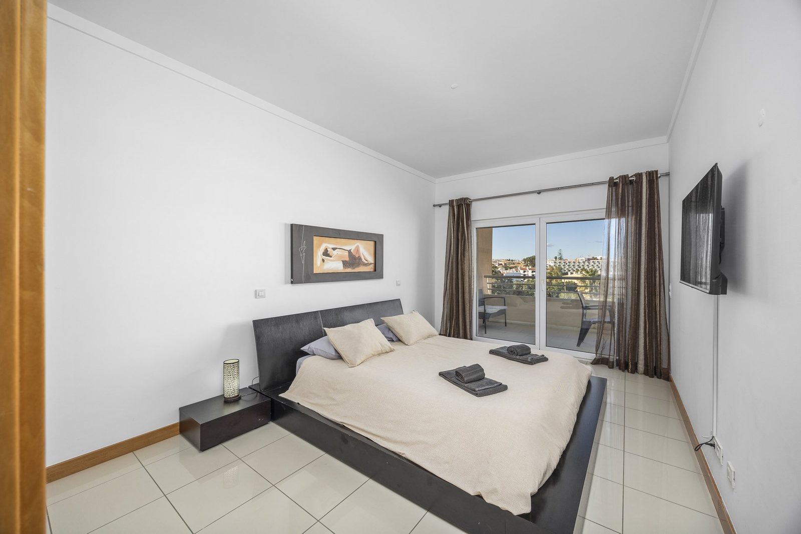 Bedroom with double bed, TV, and balcony access