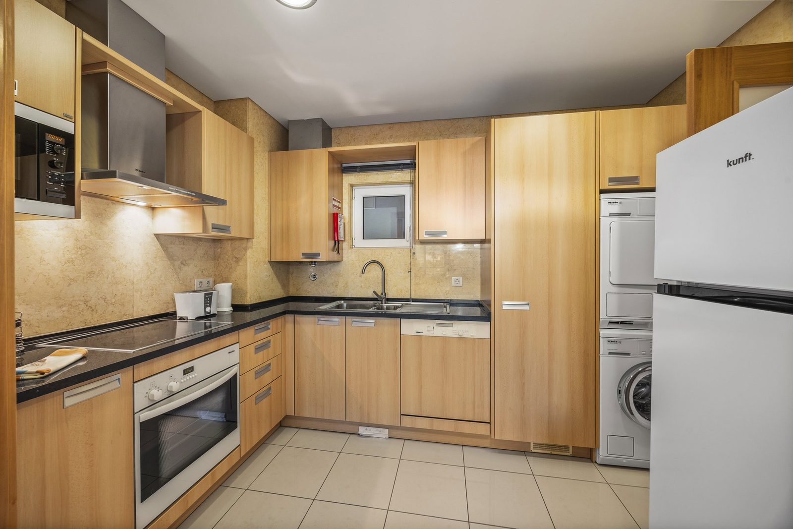 Kitchen with fridge, oven, hob, and washer-dryer