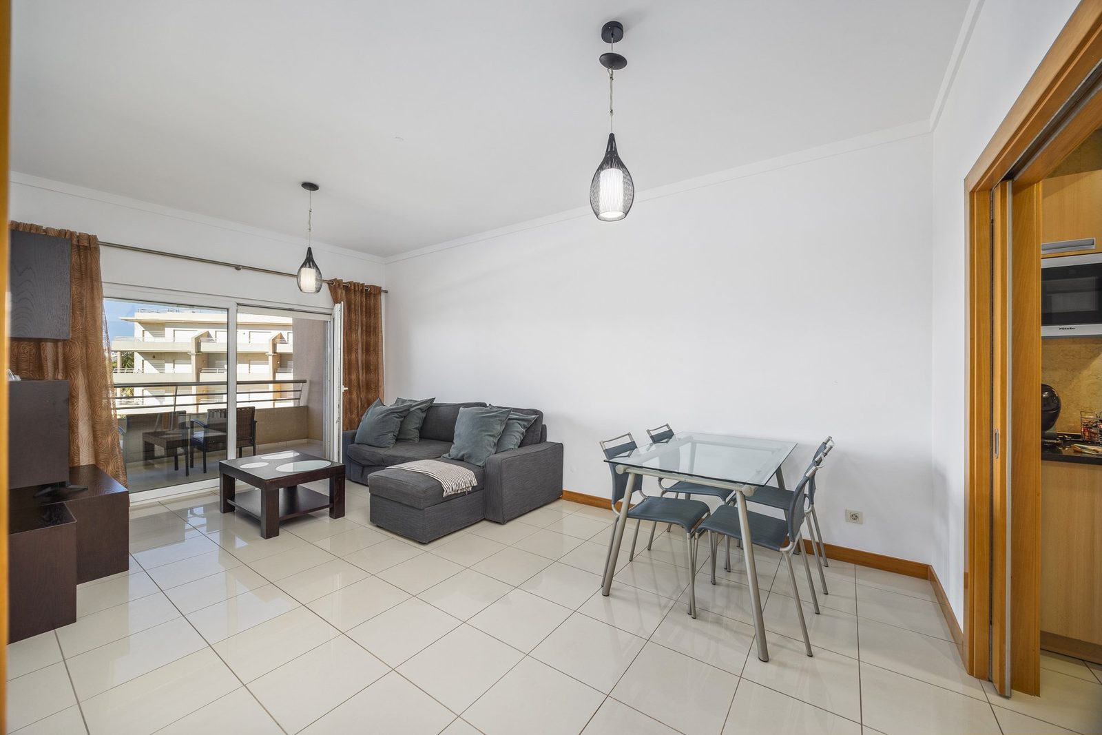 Living and dining area with sofa, dining table, and balcony access