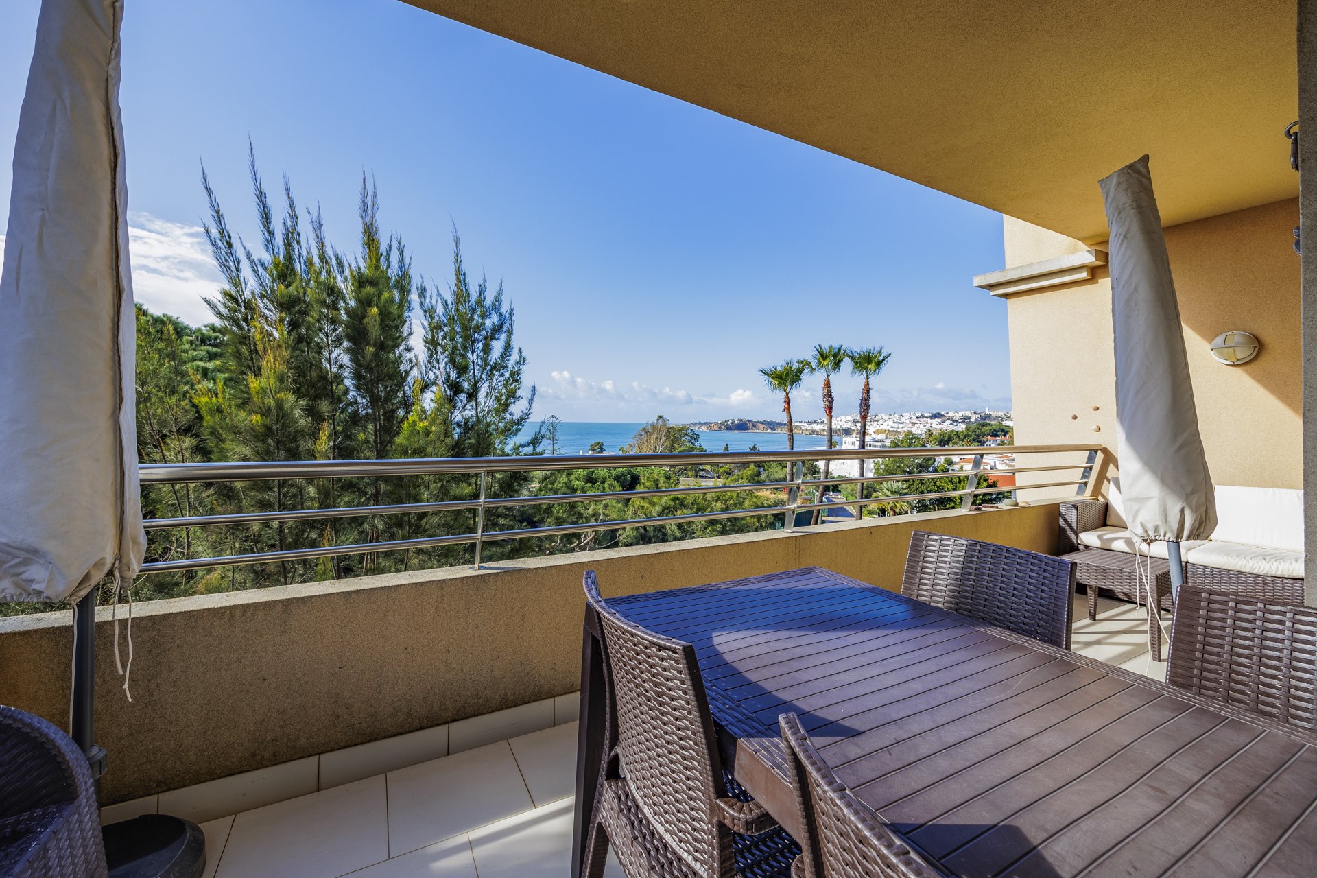 Balcony with dining table, lounge seating, palm trees, and sea view