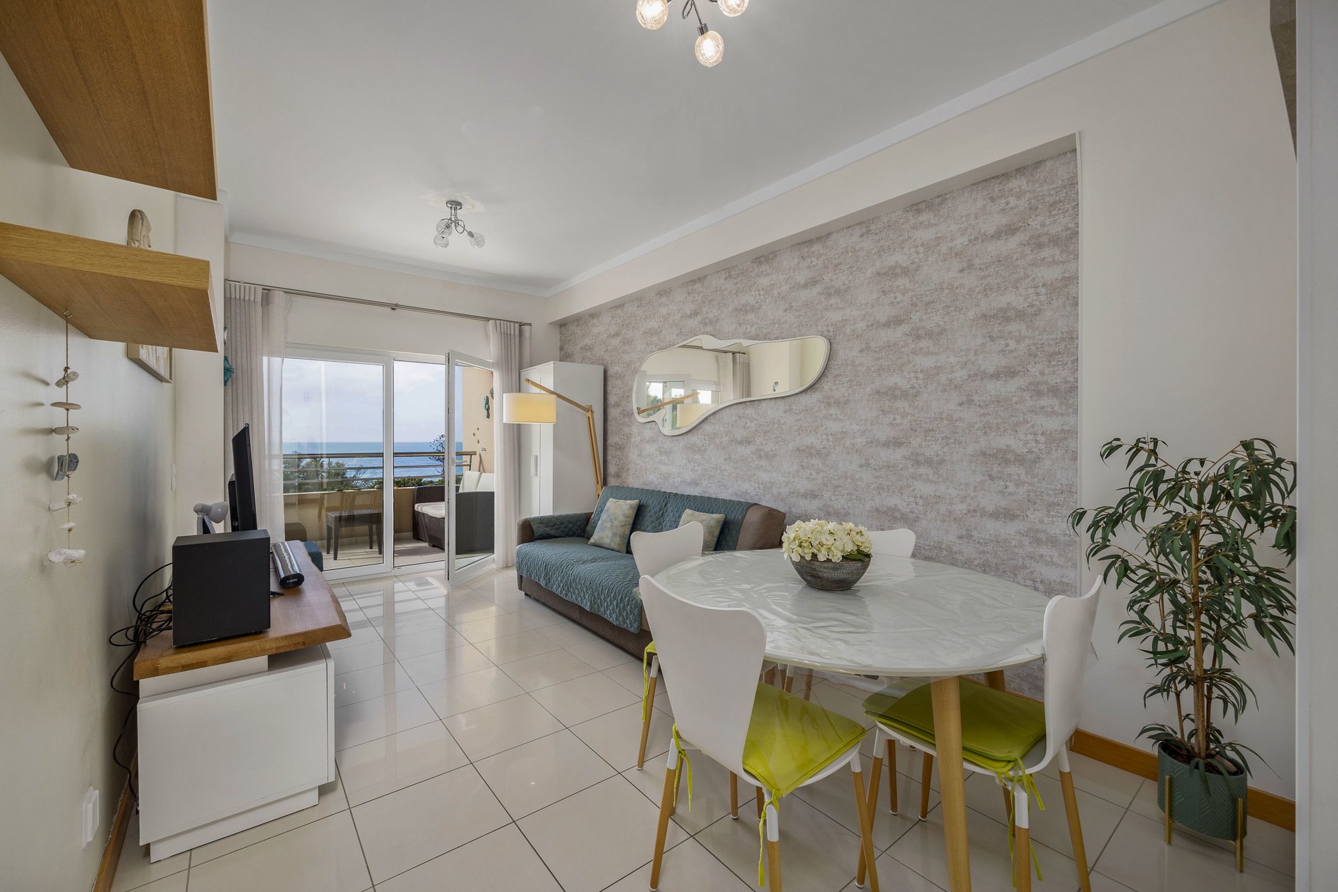 Living and dining area with sofa, dining table, and sea view balcony