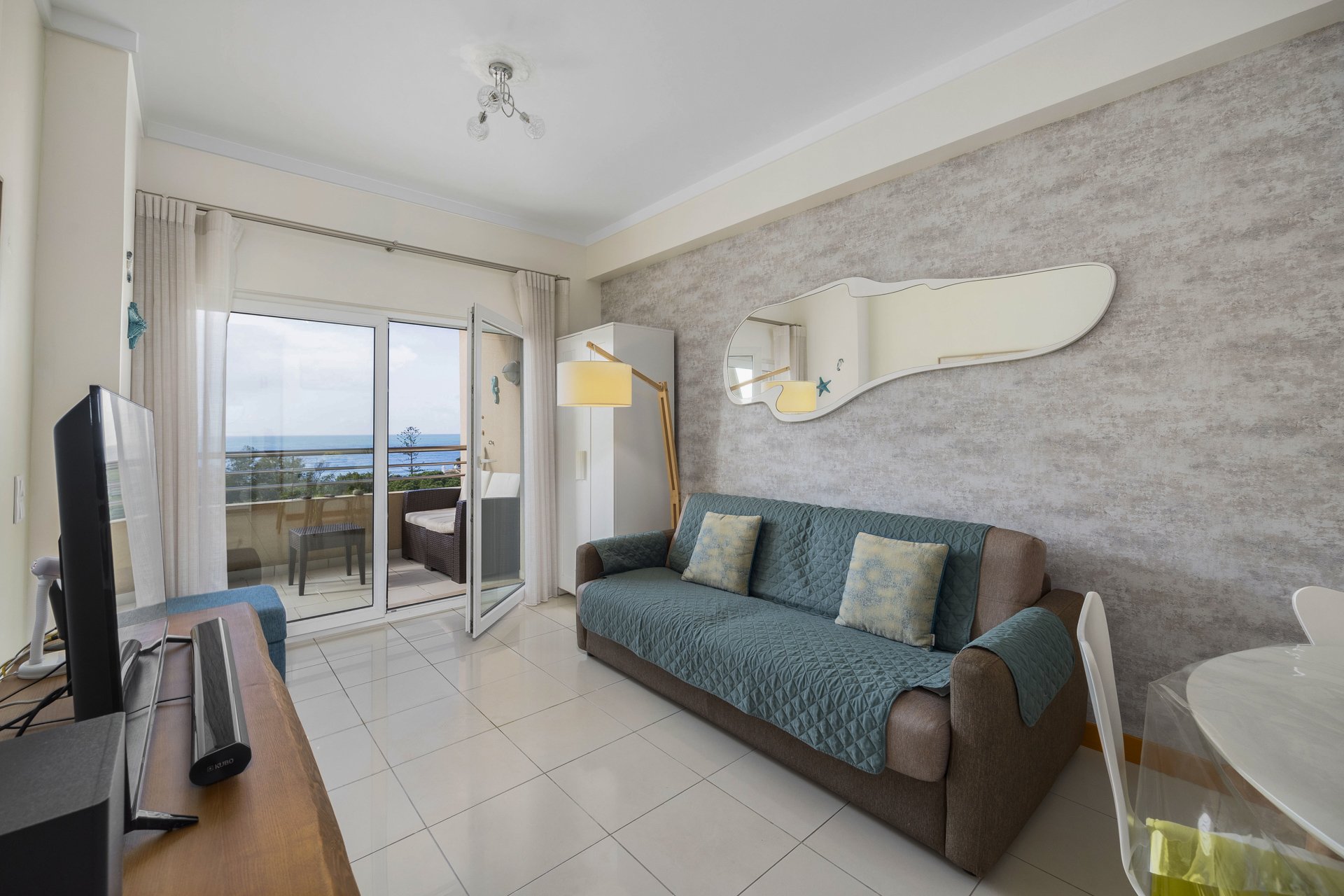 Living room with sofa and sea view through open balcony doors
