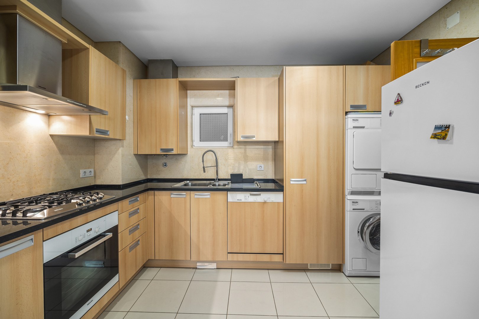 Kitchen with fridge, oven, and stacked washer-dryer