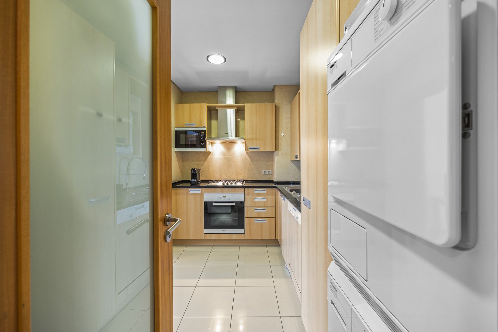 Kitchen viewed through the hallway door, with laundry area alongside