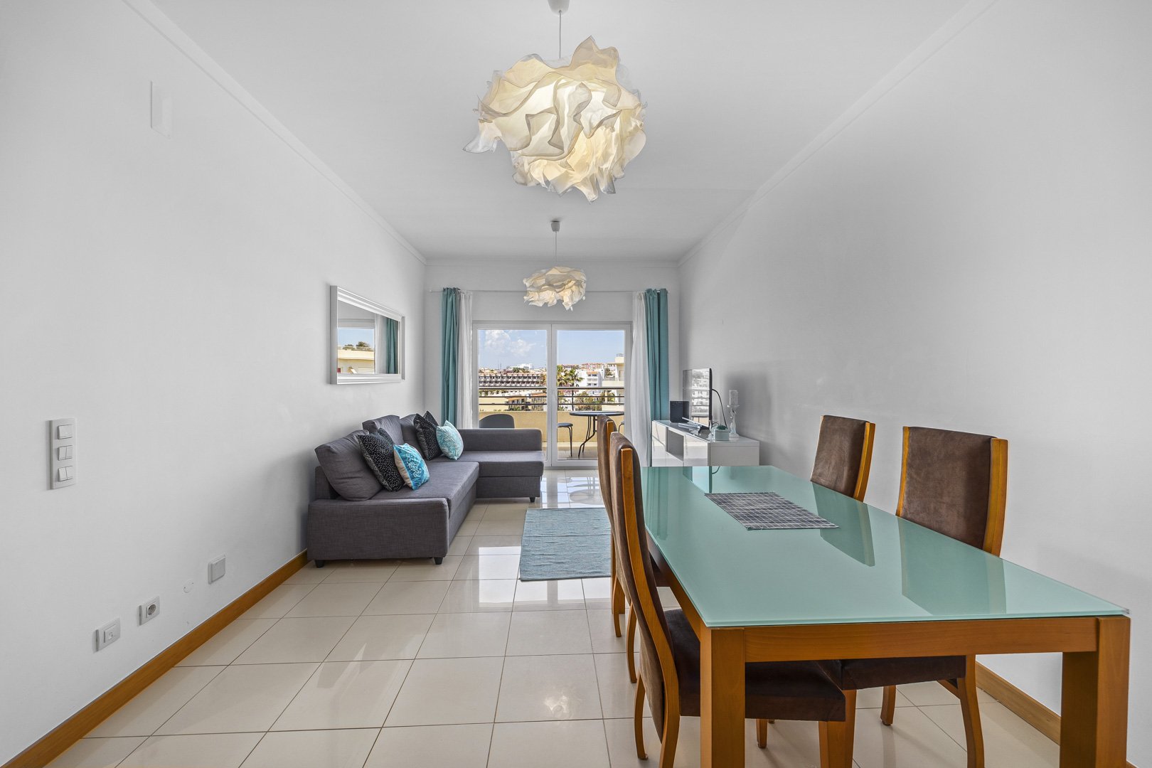 Living and dining area with mirror, sofa, and kitchen access