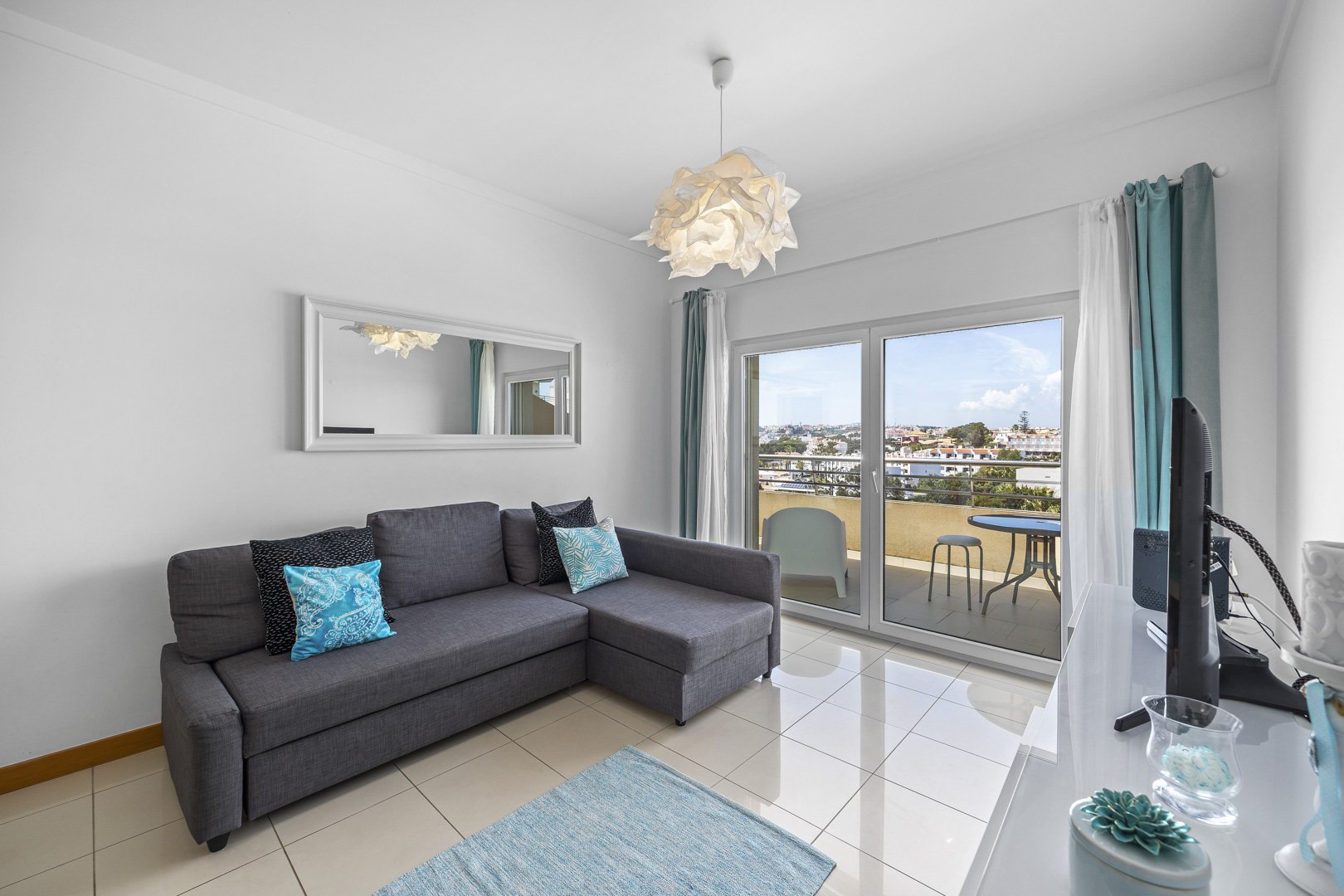 Living room with sofa and mirror, balcony access with sea view
