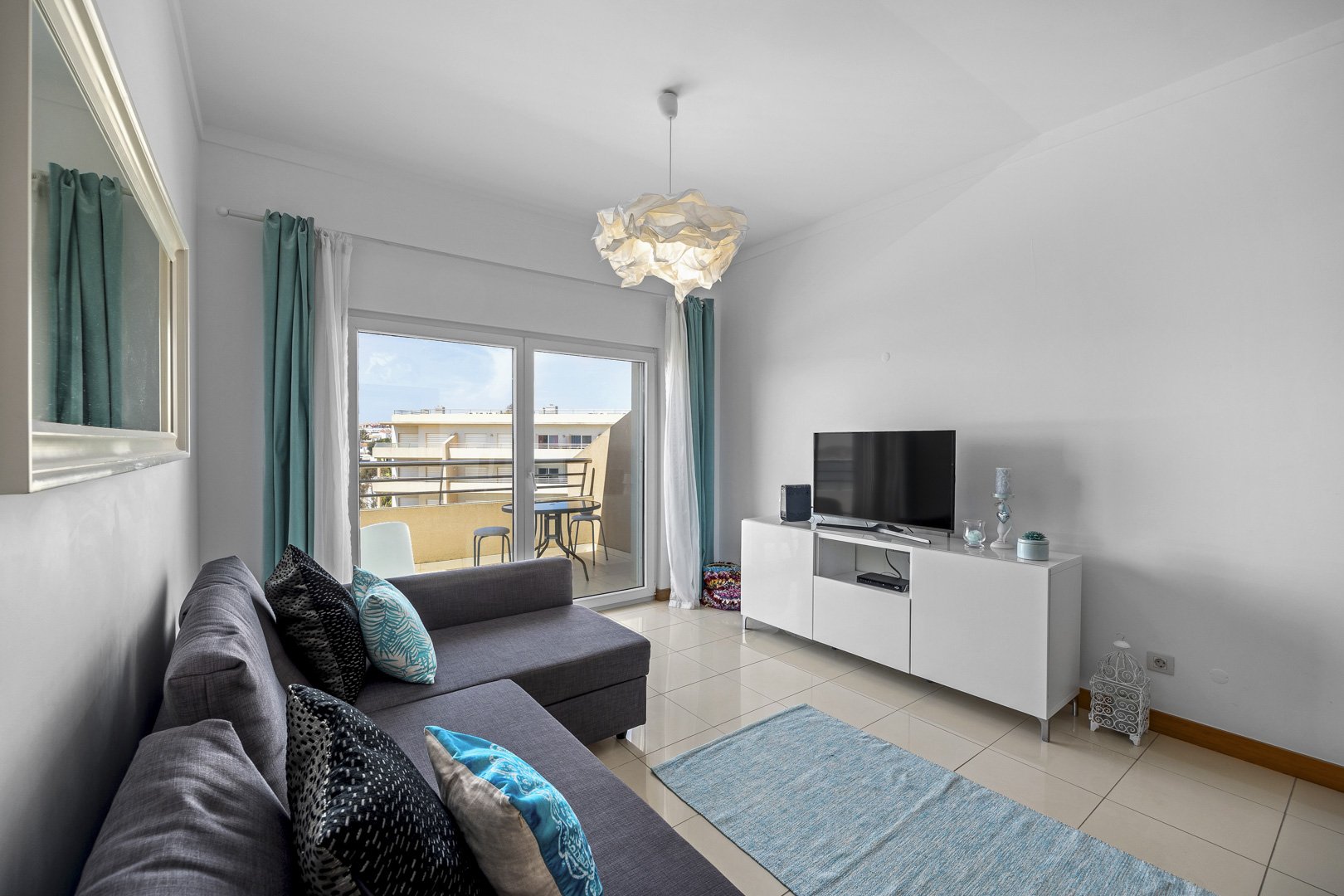 Living room with sofa, TV, and balcony access