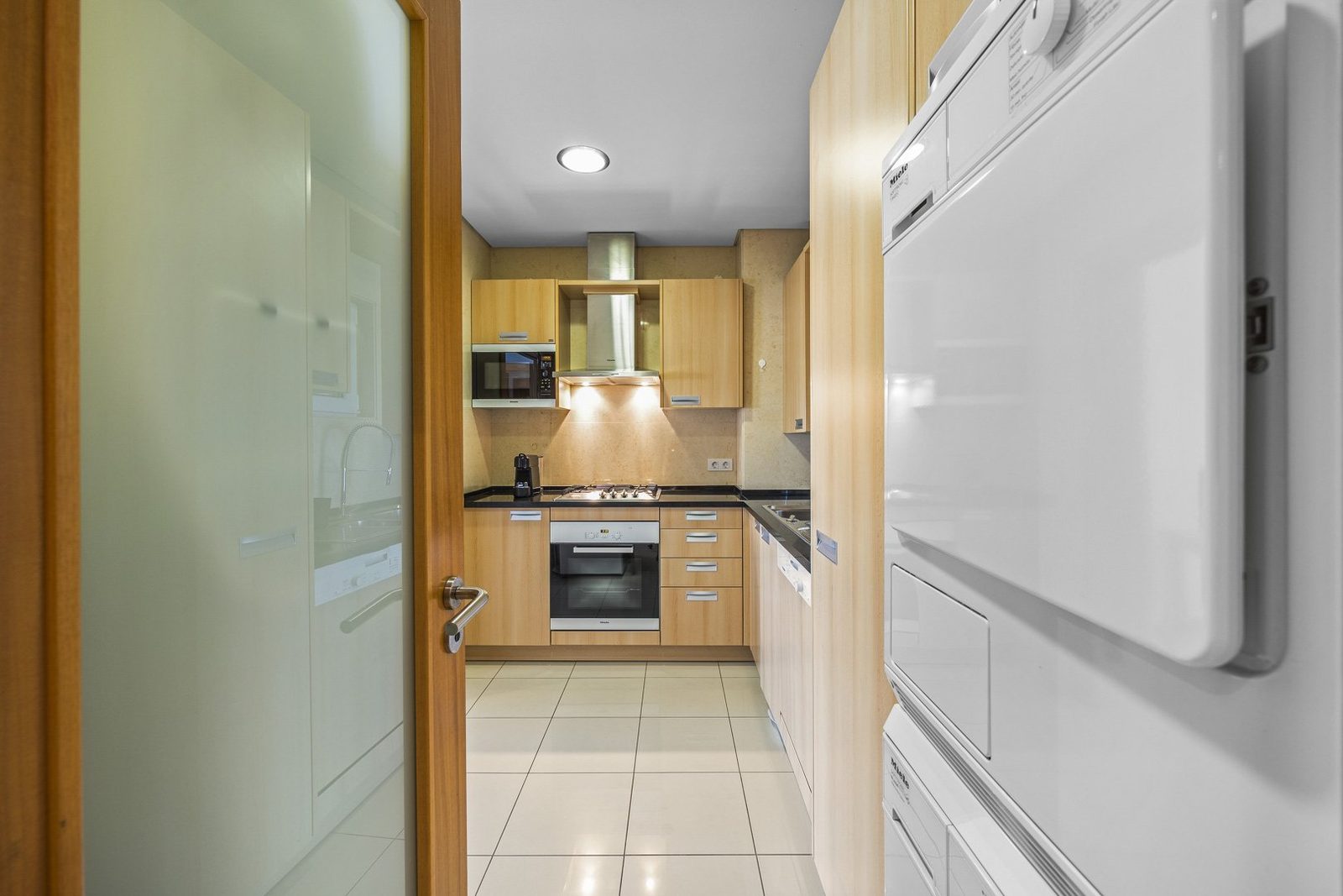 Kitchen viewed through the hallway door, with laundry area alongside