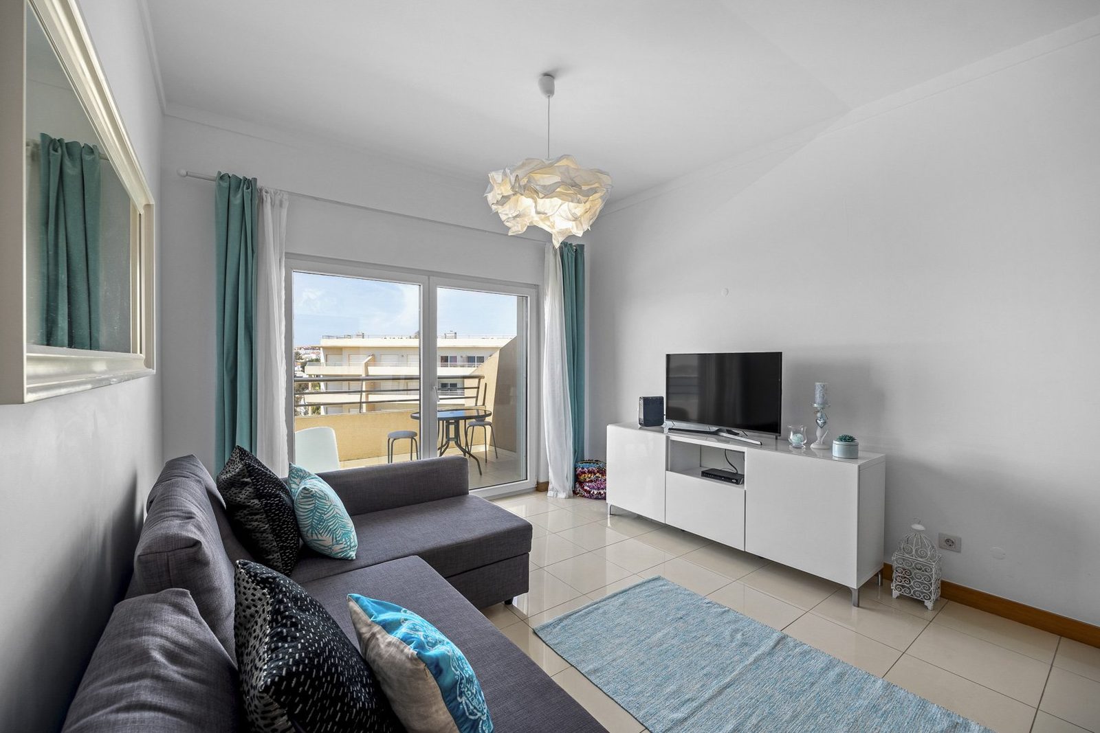 Living room with sofa, TV, and balcony access