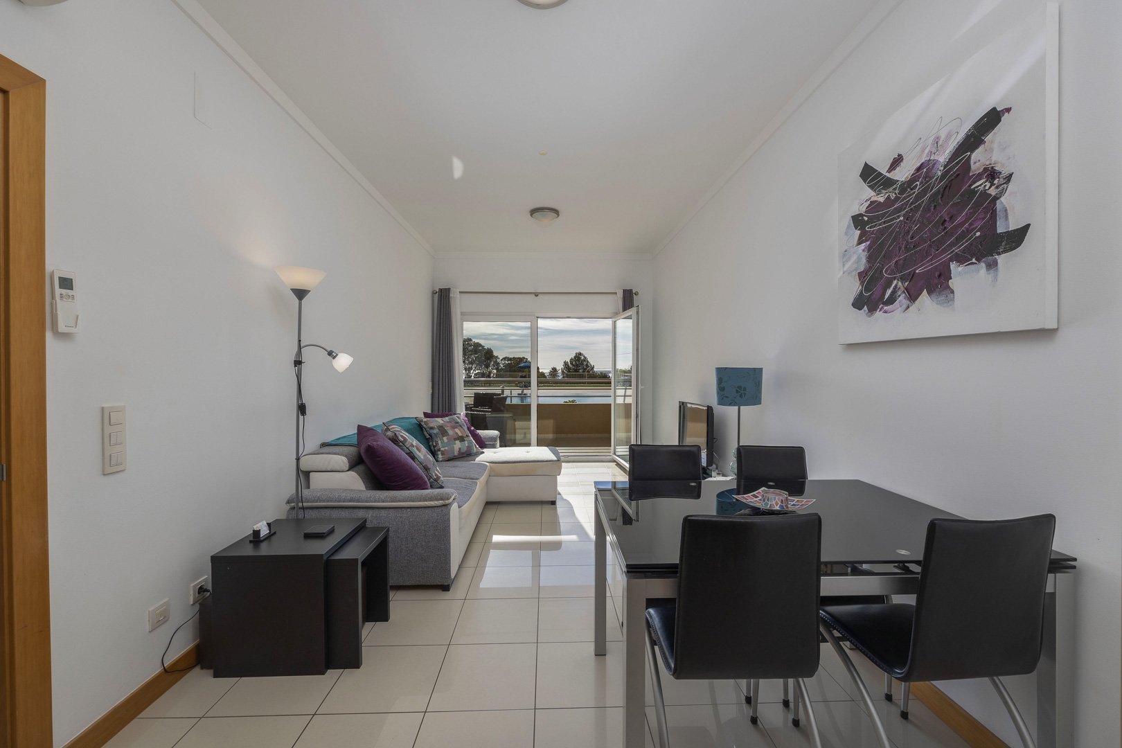 Living room with sofa, dining table, and balcony access