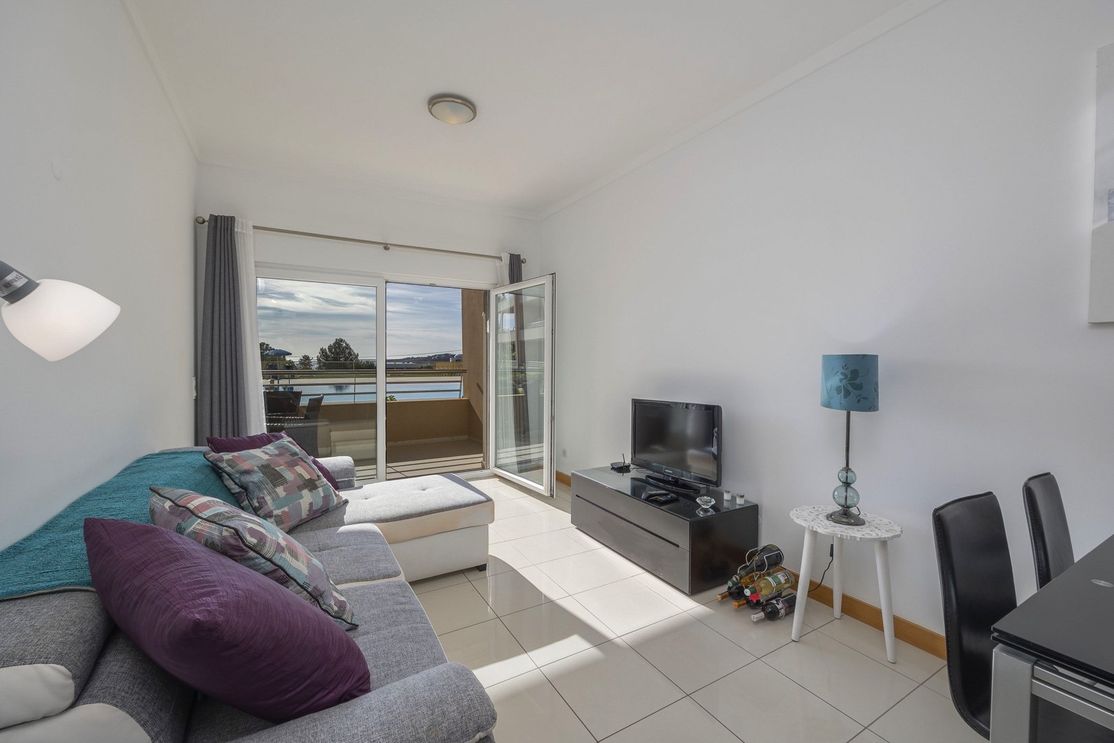 Living room with sofa, TV, and balcony access