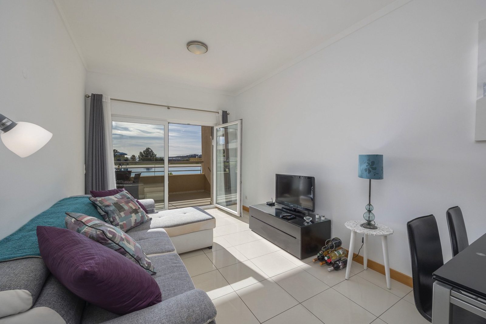 Living room with sofa, TV, and balcony access