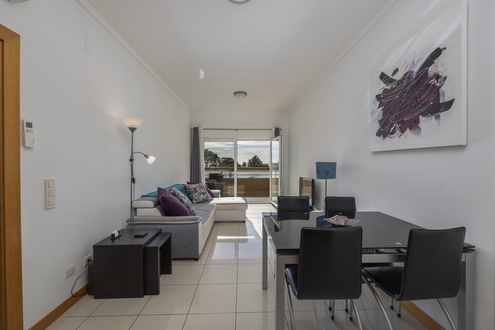 Living room with sofa, dining table, and balcony access