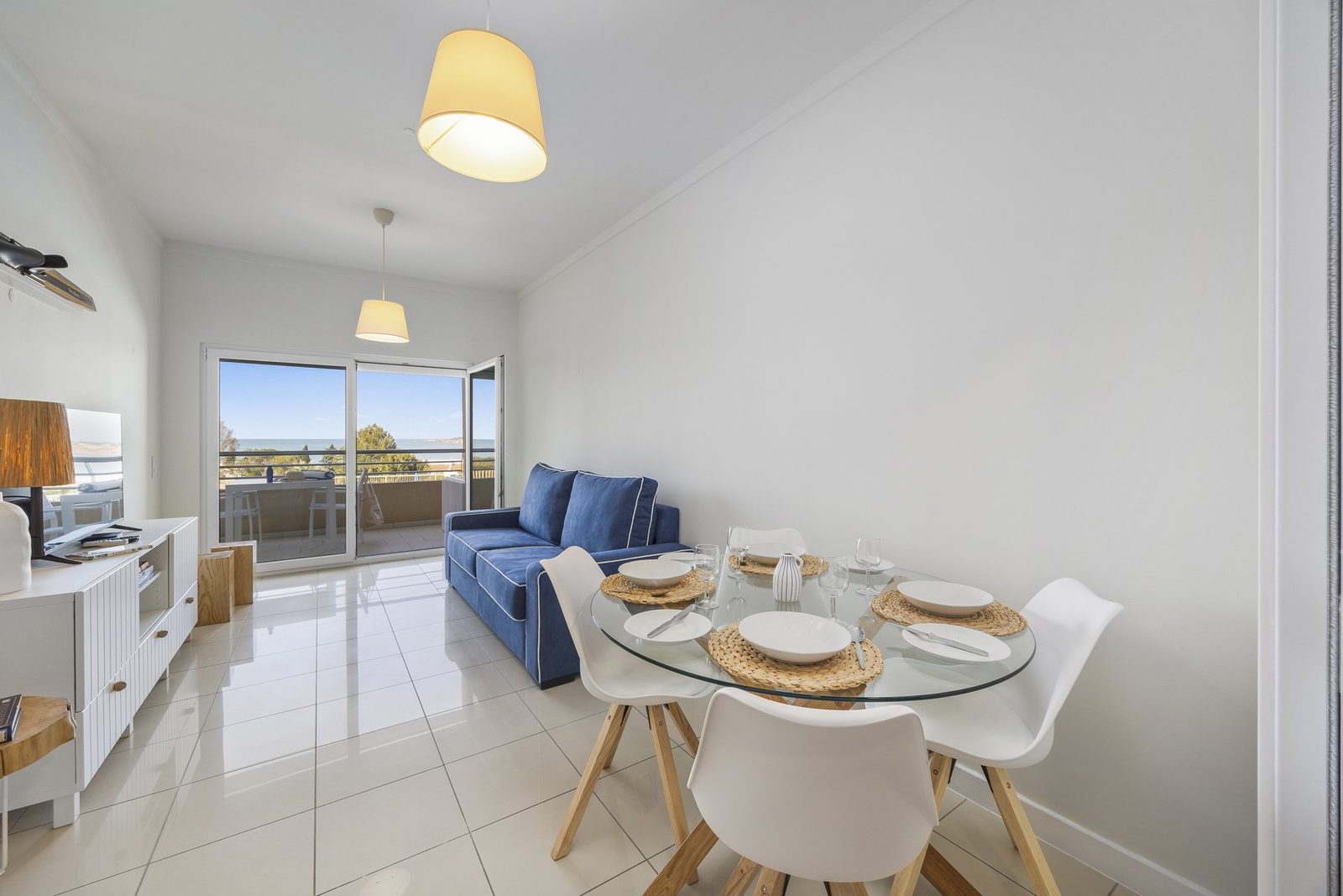 Dining table set for four with sofa and balcony access