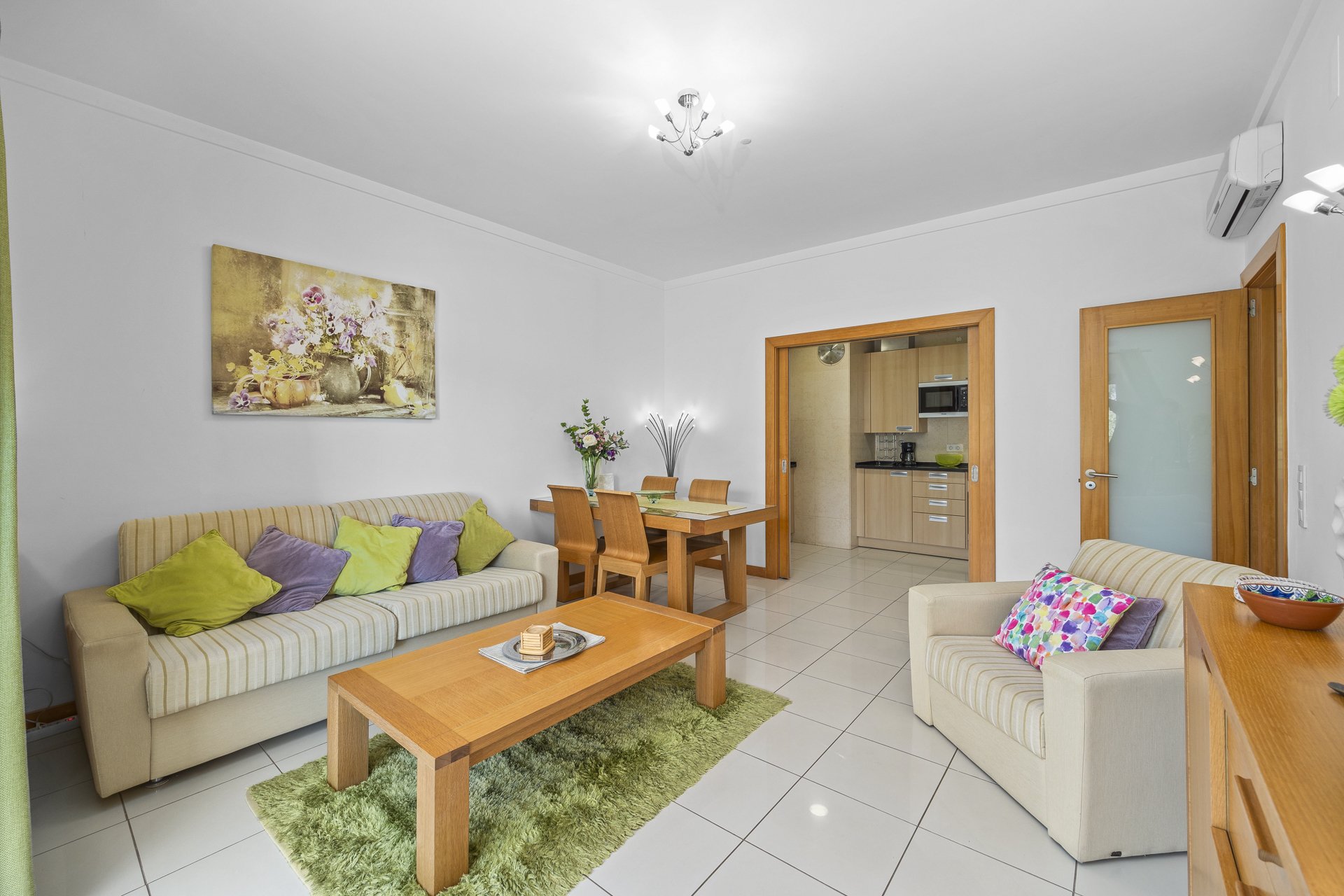 Living and dining area with sofa, dining table, and kitchen access