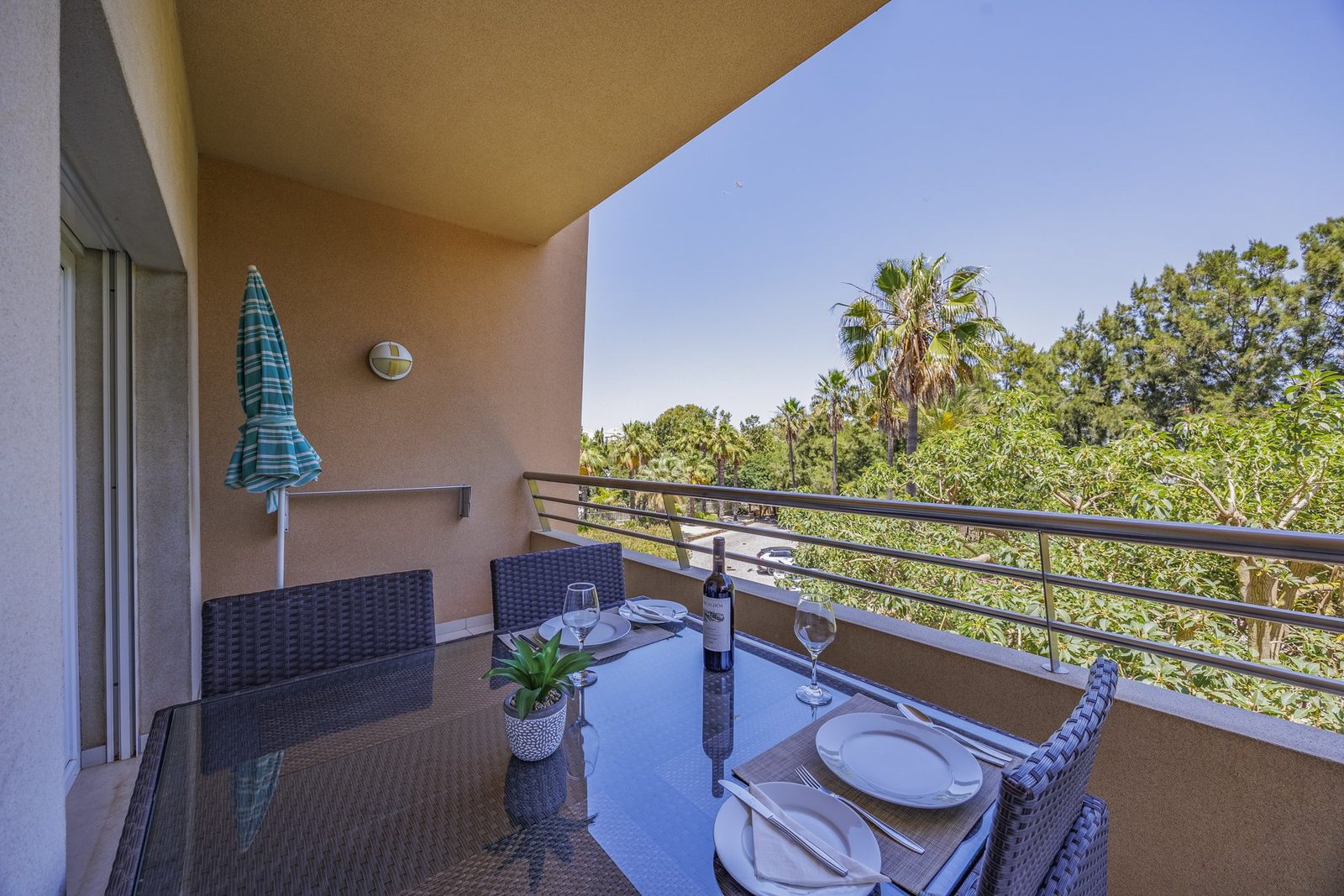 Balcony dining table set for a meal with umbrella and treed view