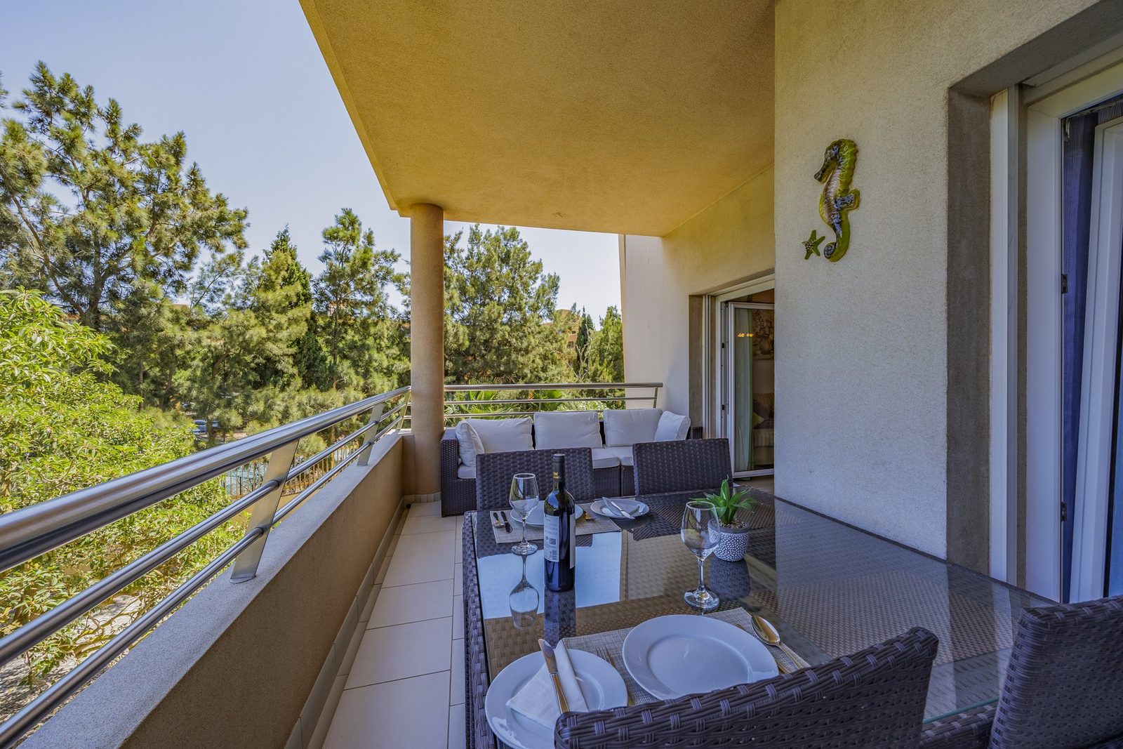 Balcony dining table with wine glasses and treed view