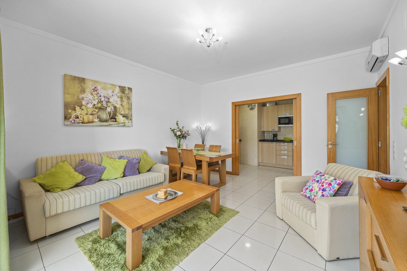 Living and dining area with sofa, dining table, and kitchen access