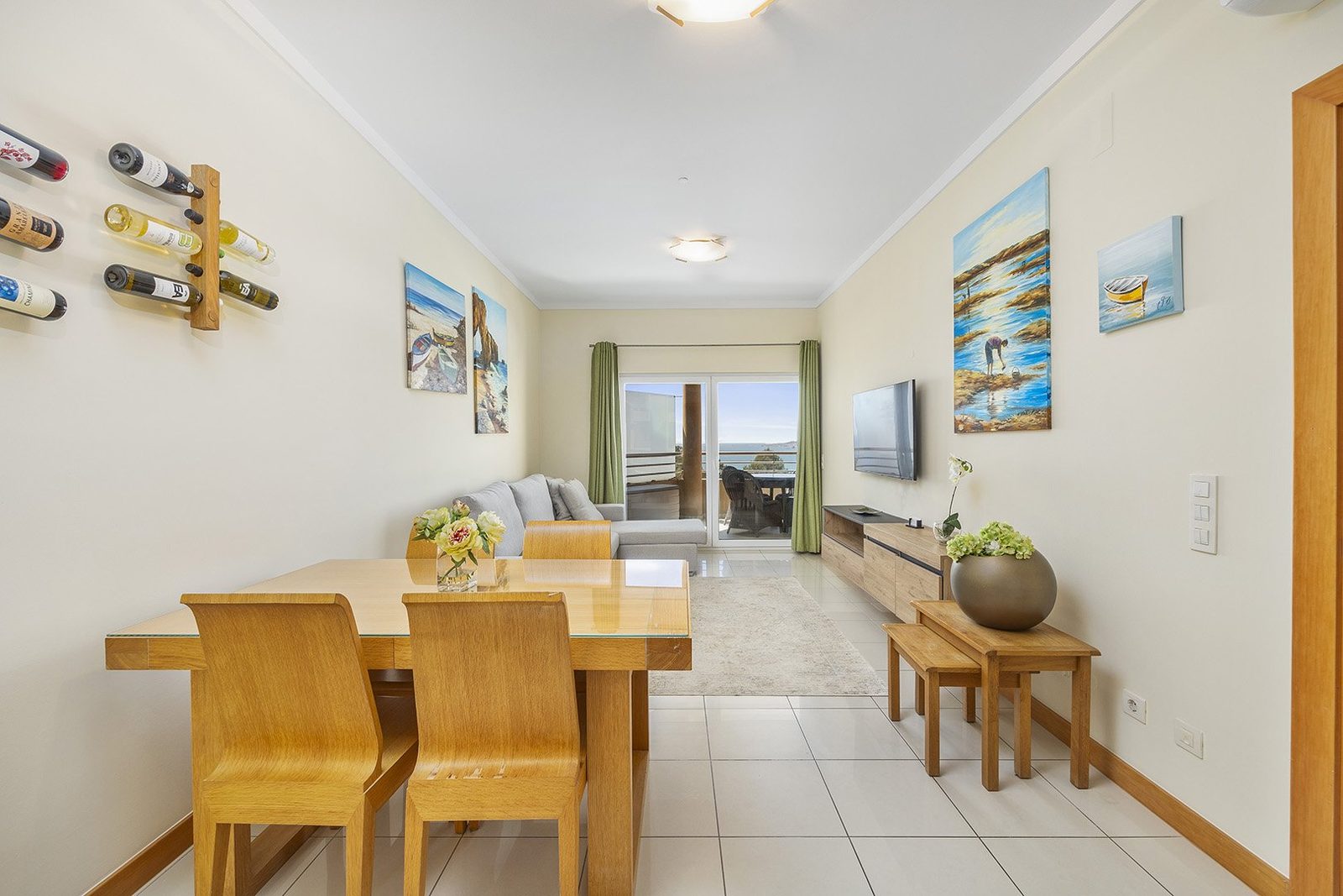 Living and dining area with wine rack, dining table, and sea view balcony