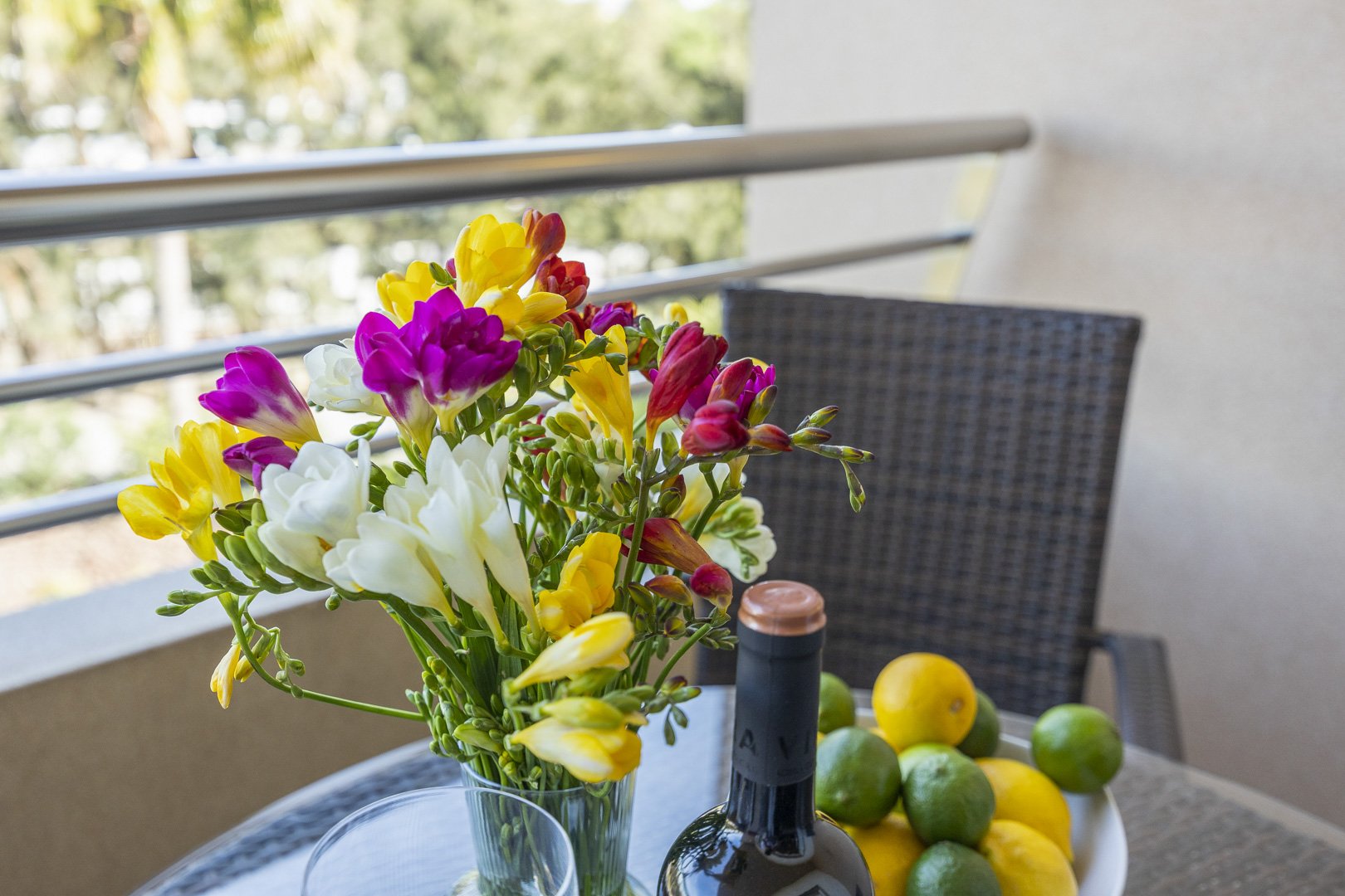 Balcony table with fresh flowers, wine, and fruit