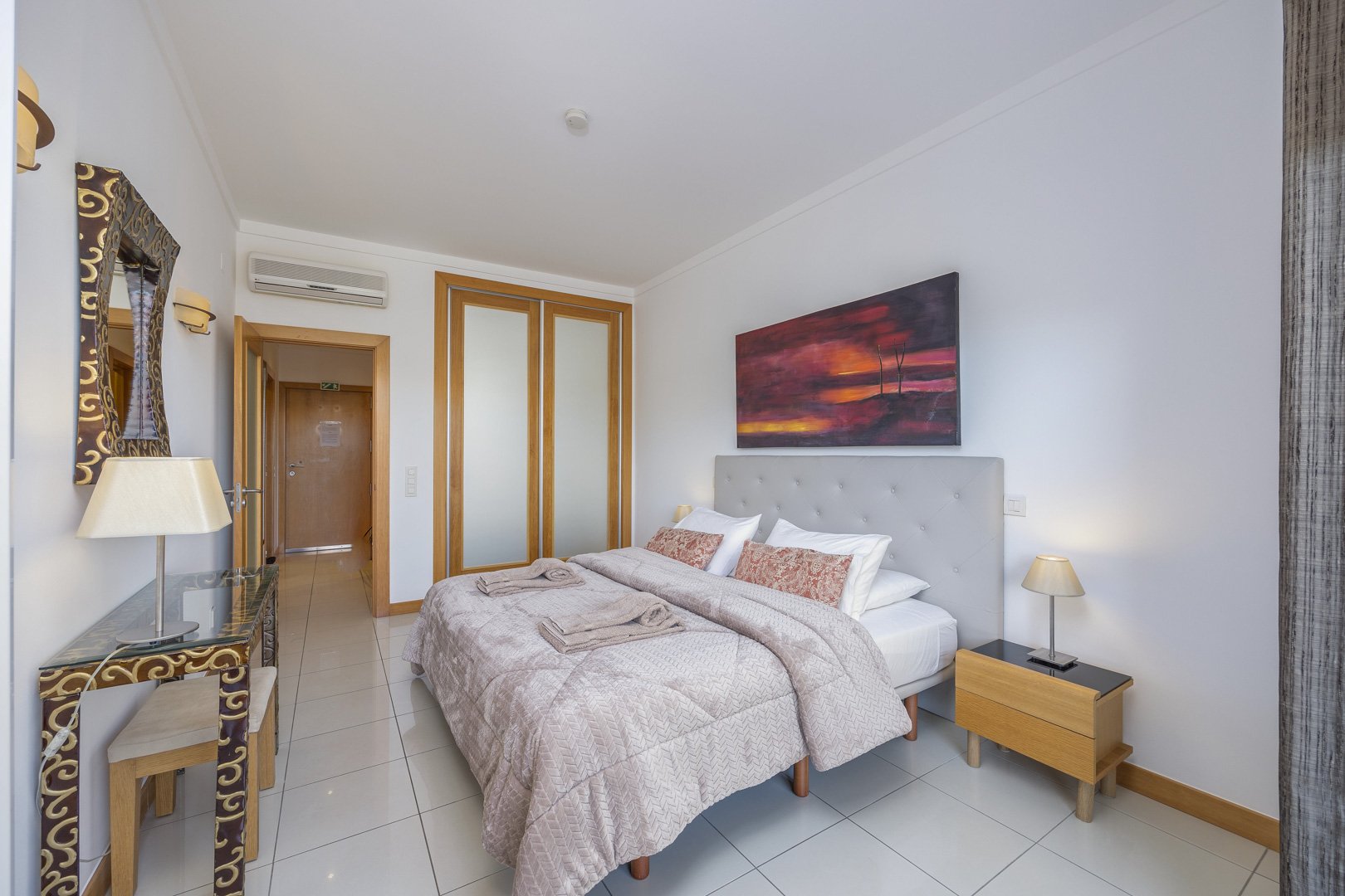 Bedroom with double bed, console table, and artwork