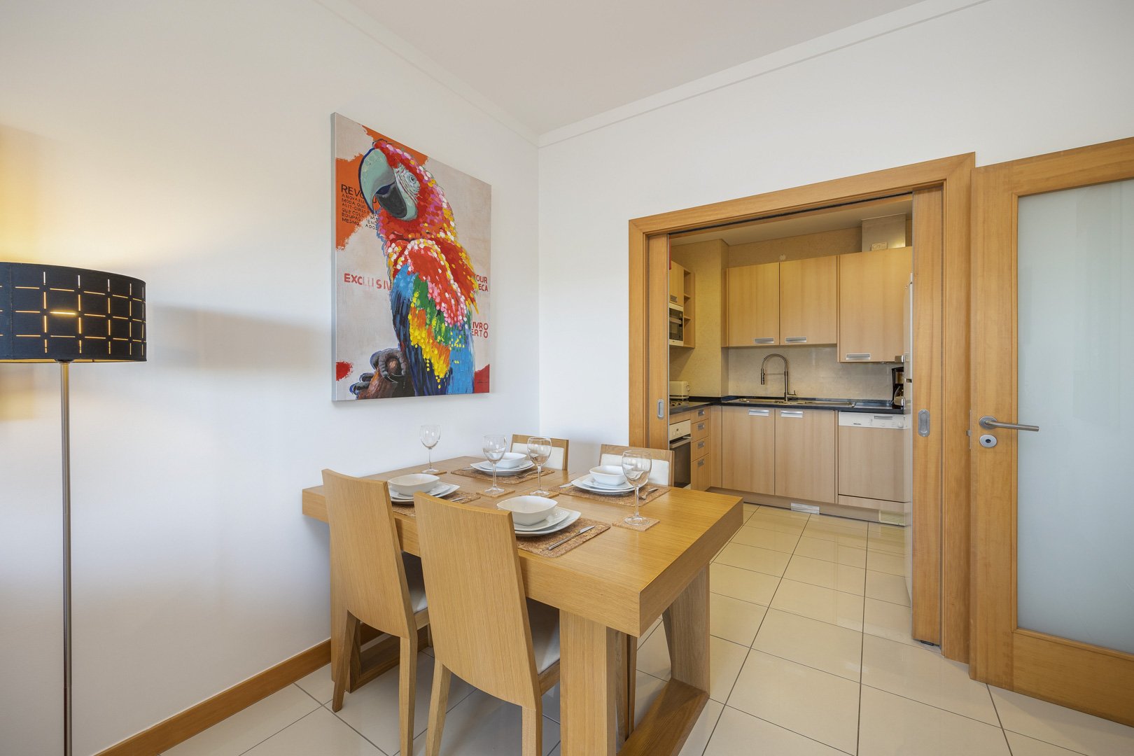 Dining table with view through to the kitchen, parrot artwork on the wall