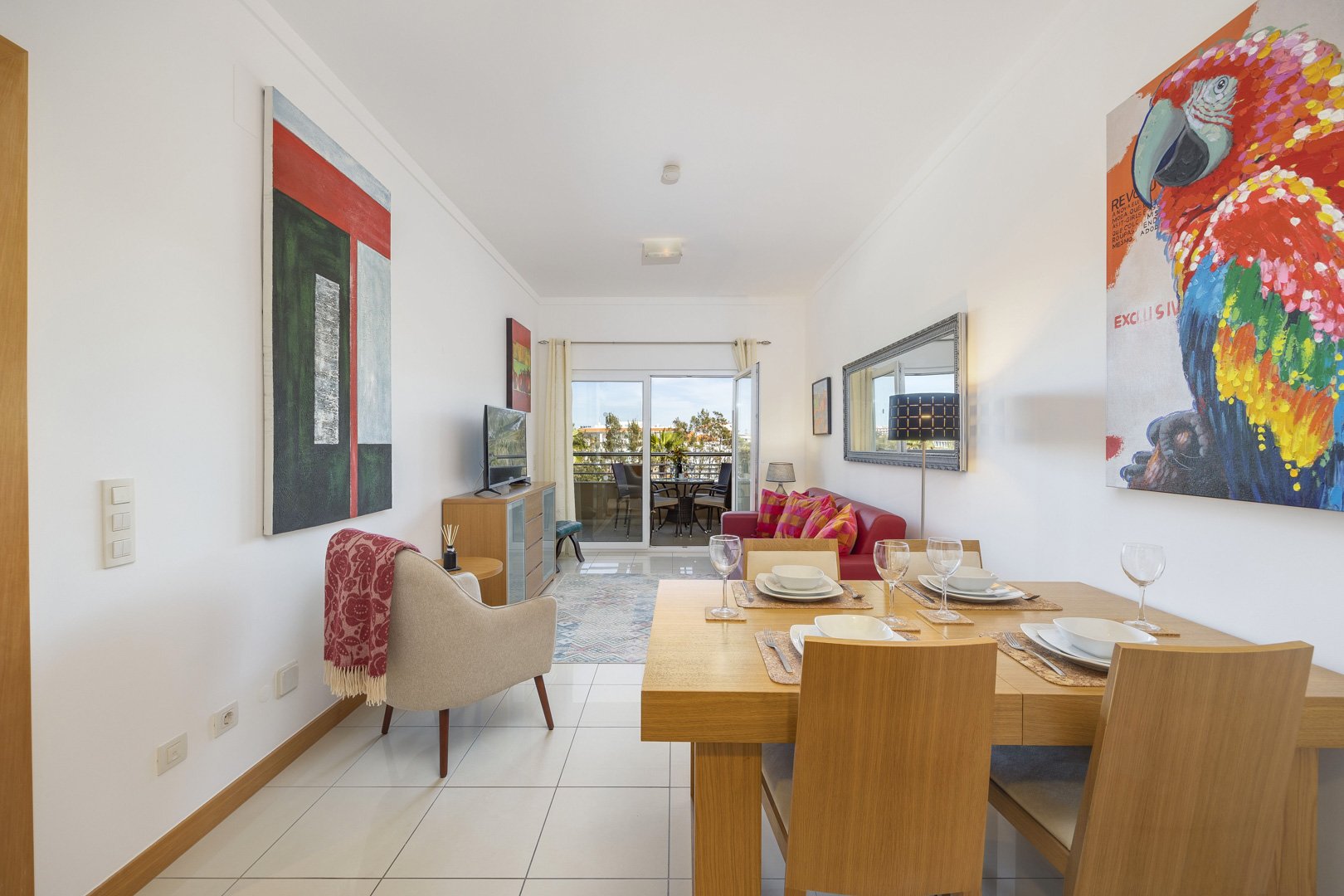 Living and dining area with red sofa, dining table, and balcony access