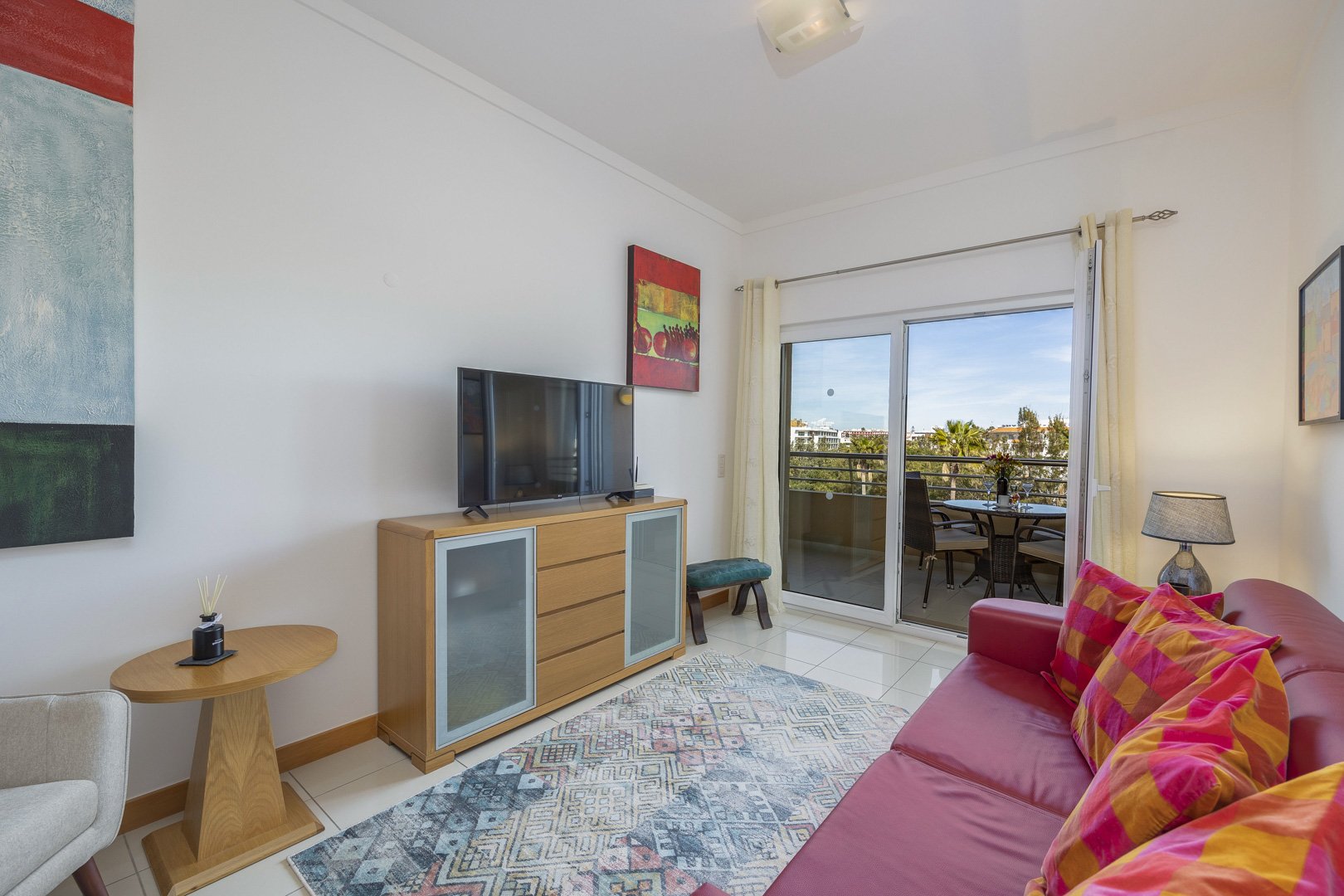 Living room with red sofa, side table, and balcony access
