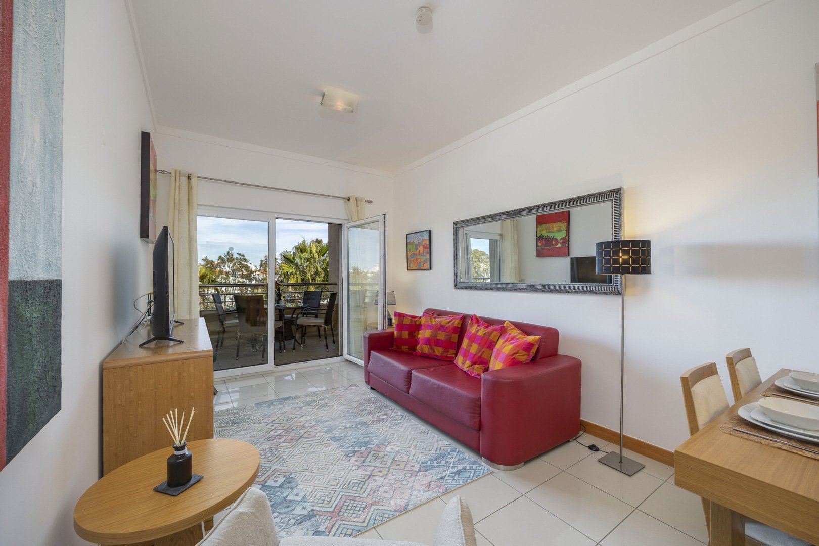Living room with red sofa, mirror, and balcony access