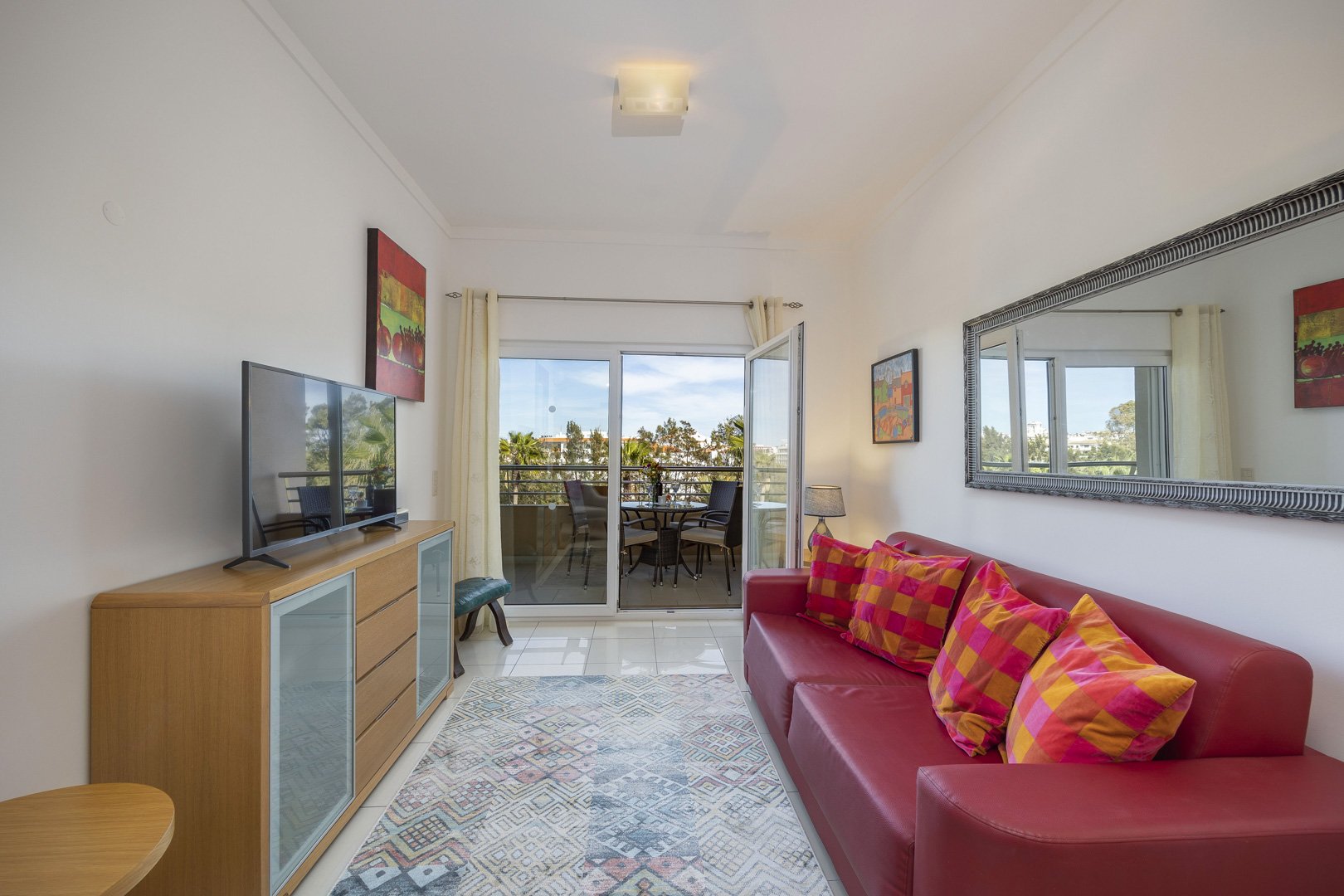 Living room with red sofa, TV, and balcony access