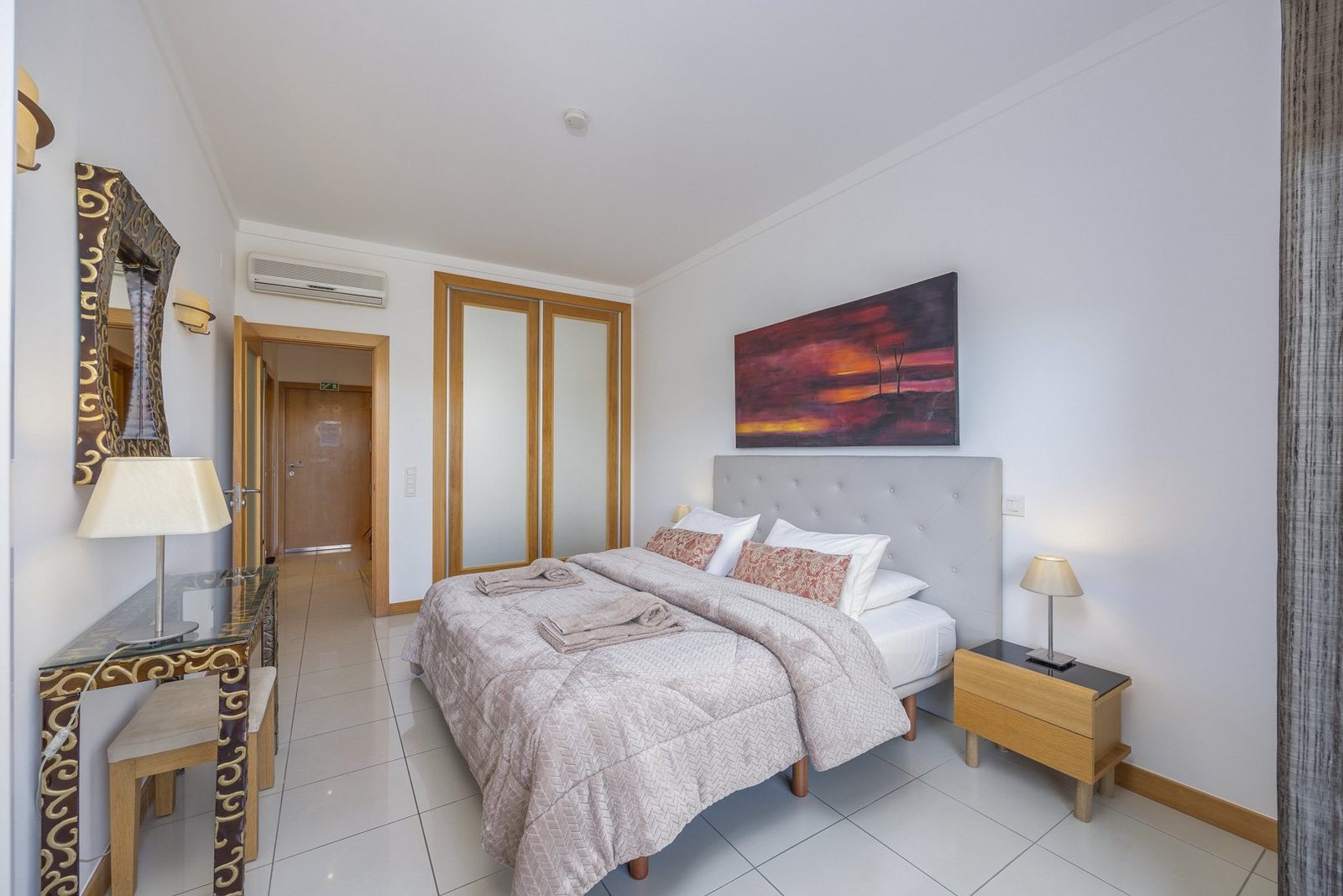 Bedroom with double bed, console table, and artwork
