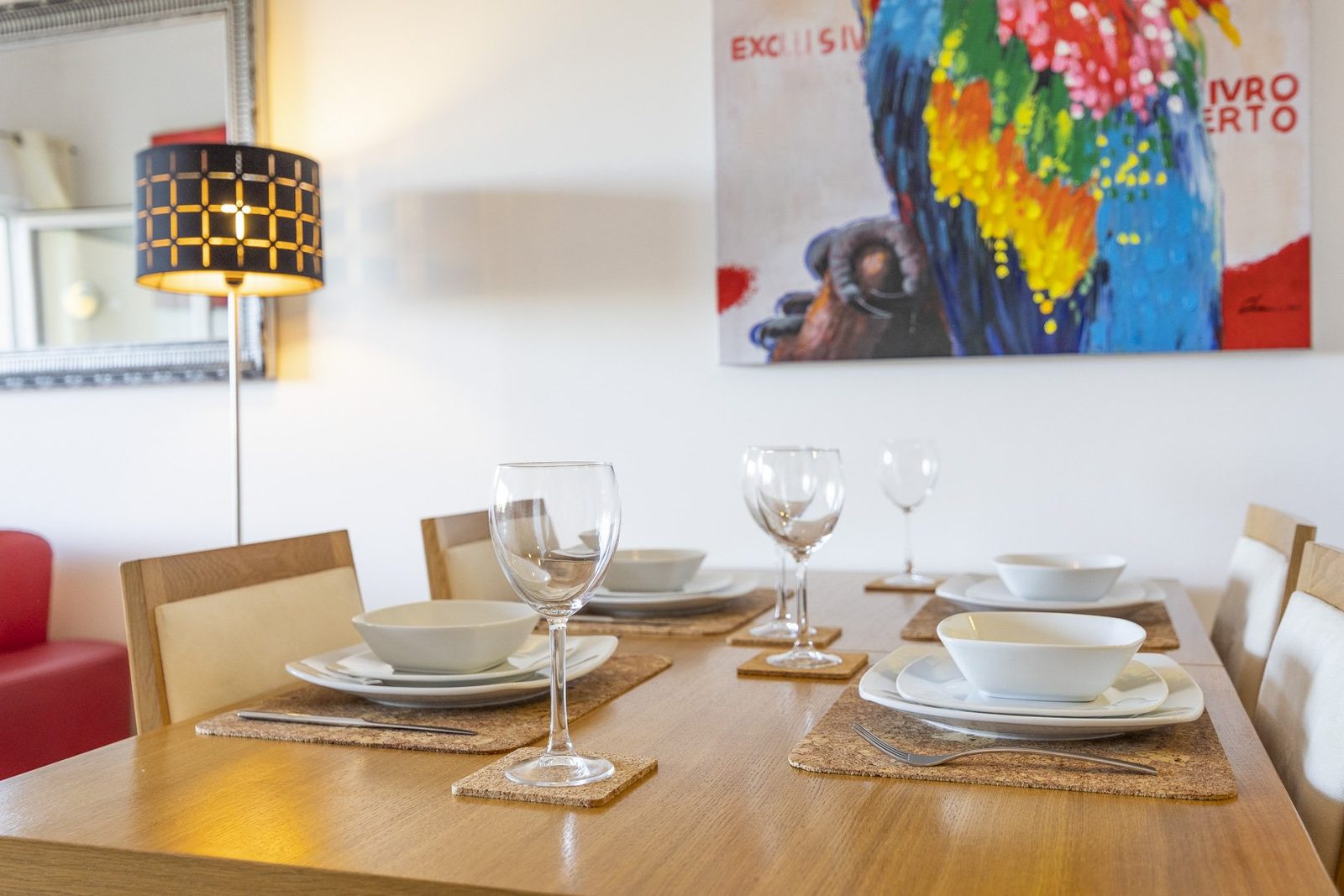 Dining table set for a meal with parrot artwork on the wall