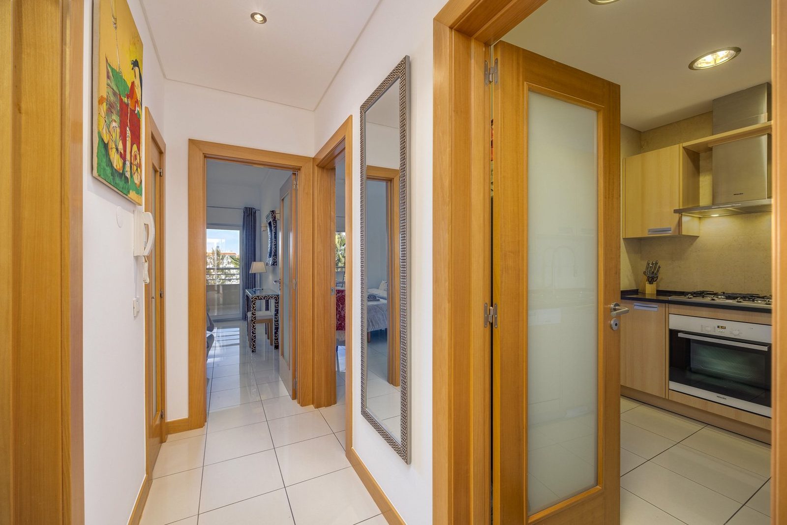 Hallway with artwork, leading to the kitchen and living areas