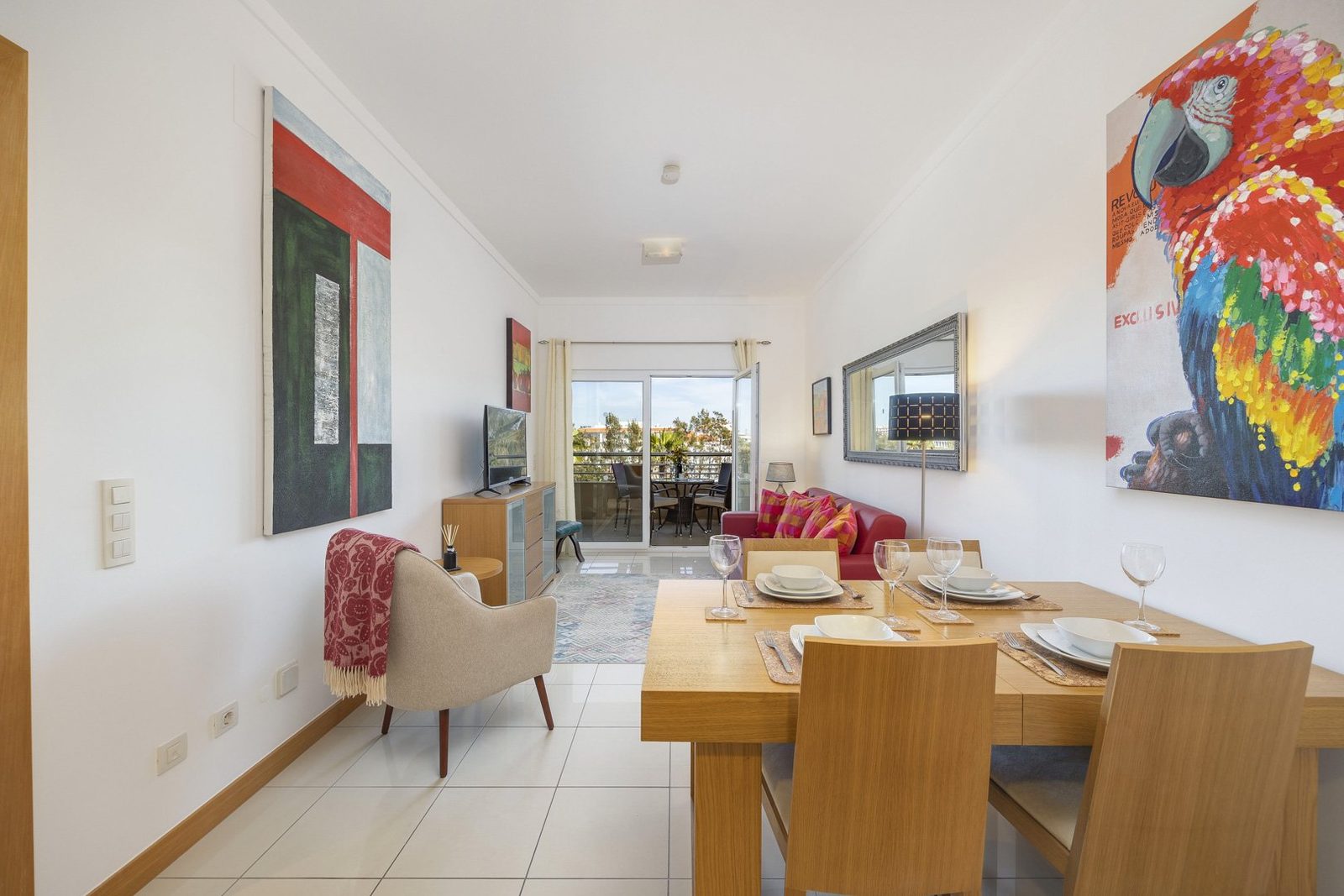 Living and dining area with red sofa, dining table, and balcony access