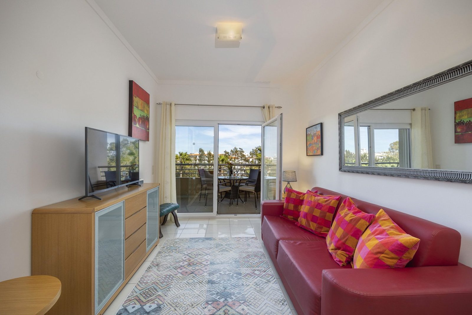 Living room with red sofa, TV, and balcony access