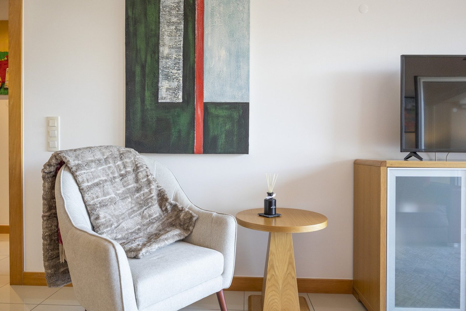 Living room with armchair, side table, and modern artwork