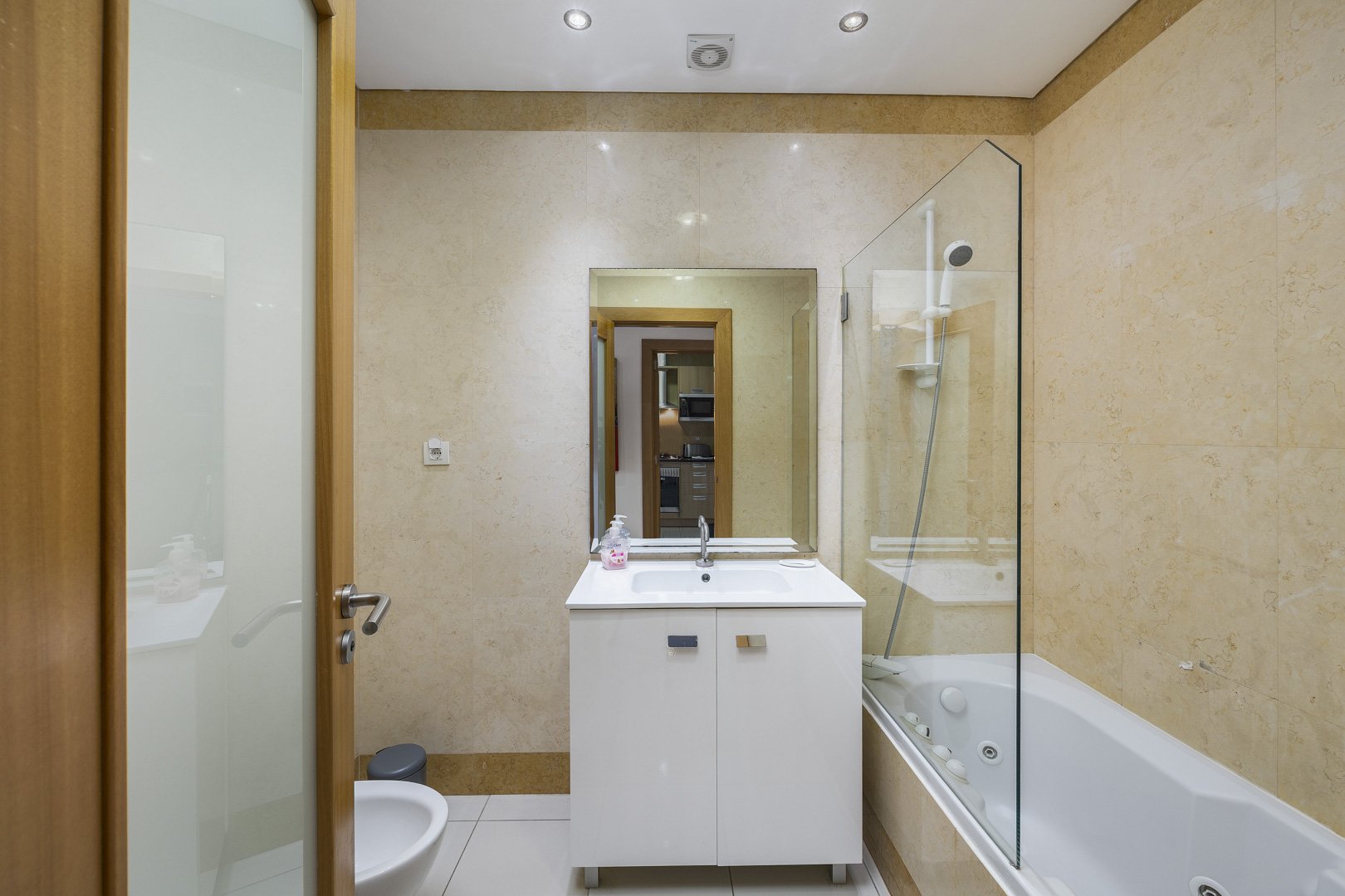 Bathroom with bathtub, glass shower screen, and vanity unit