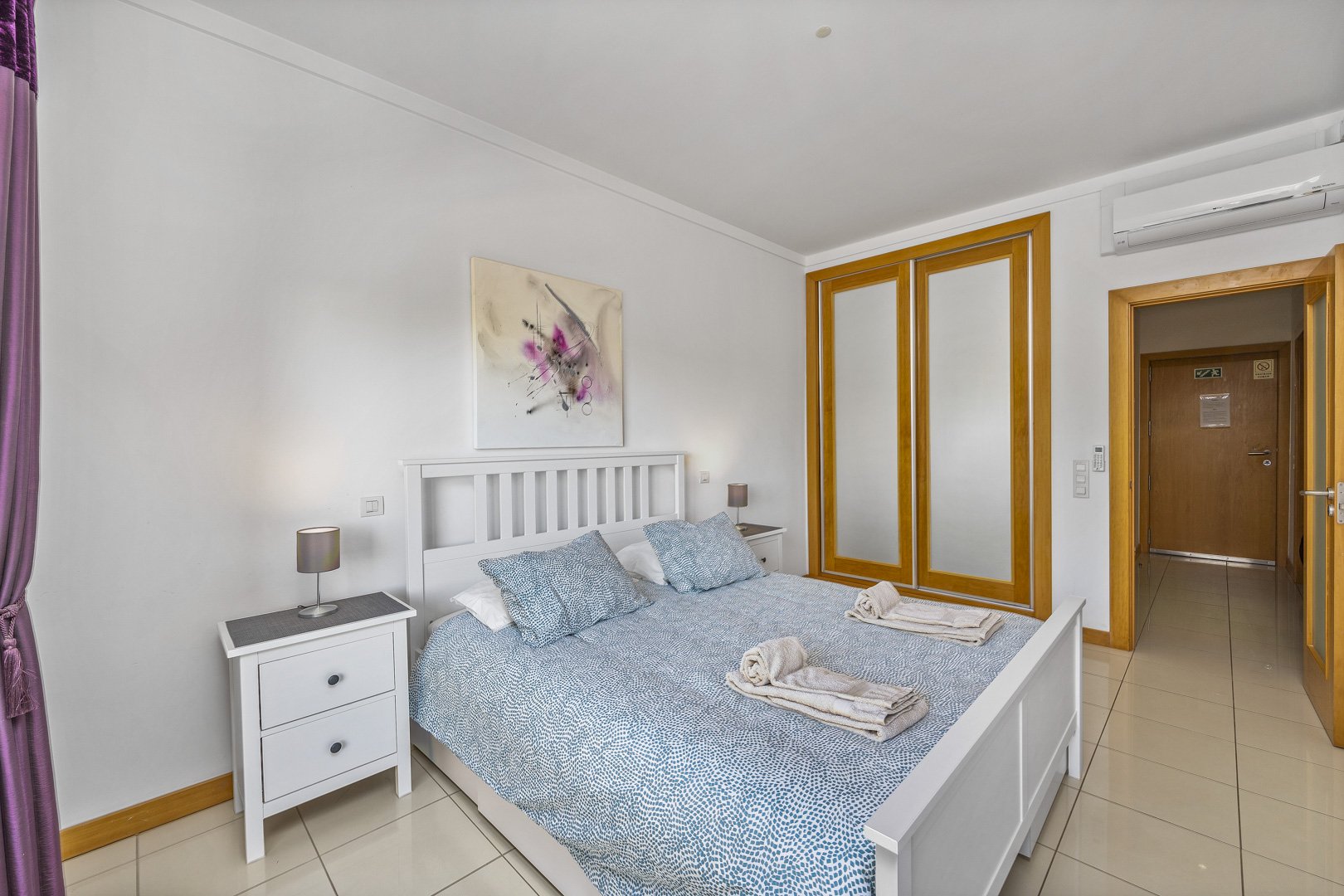 Bedroom with double bed, mirrored wardrobe, and hallway access