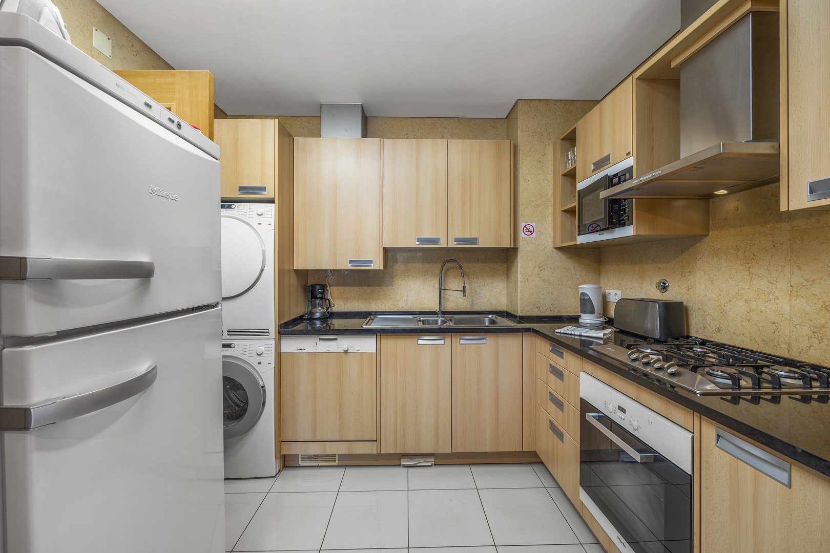 Kitchen with fridge-freezer, stacked washer-dryer, and dining area view